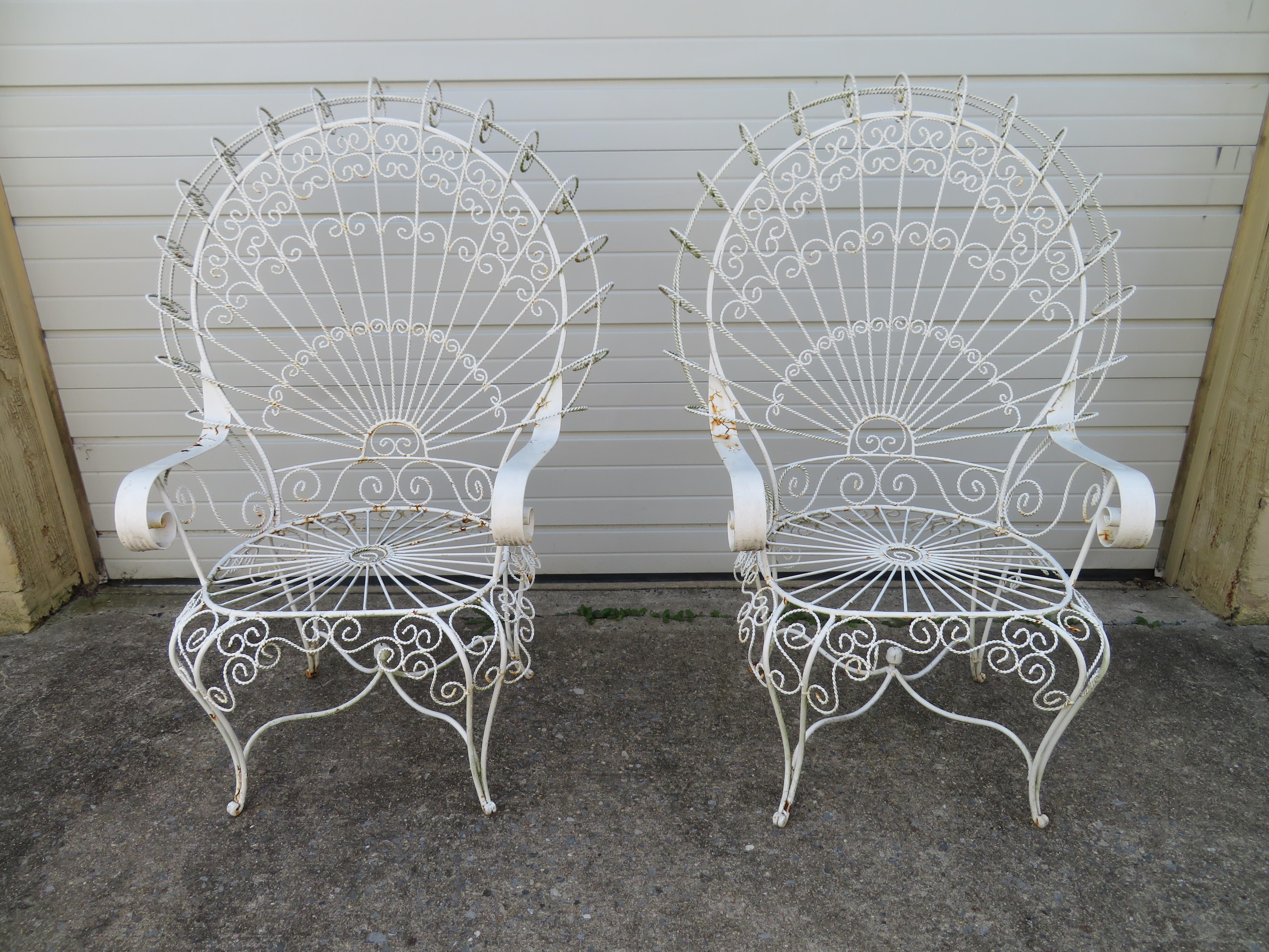 Gorgeous pair of Salterini style ornate wrought iron twisted wire fan back patio chairs. This pair is in vintage condition retaining their original white finish-shows wear to arms. There are no cracks or breaks to the frames-sturdy.