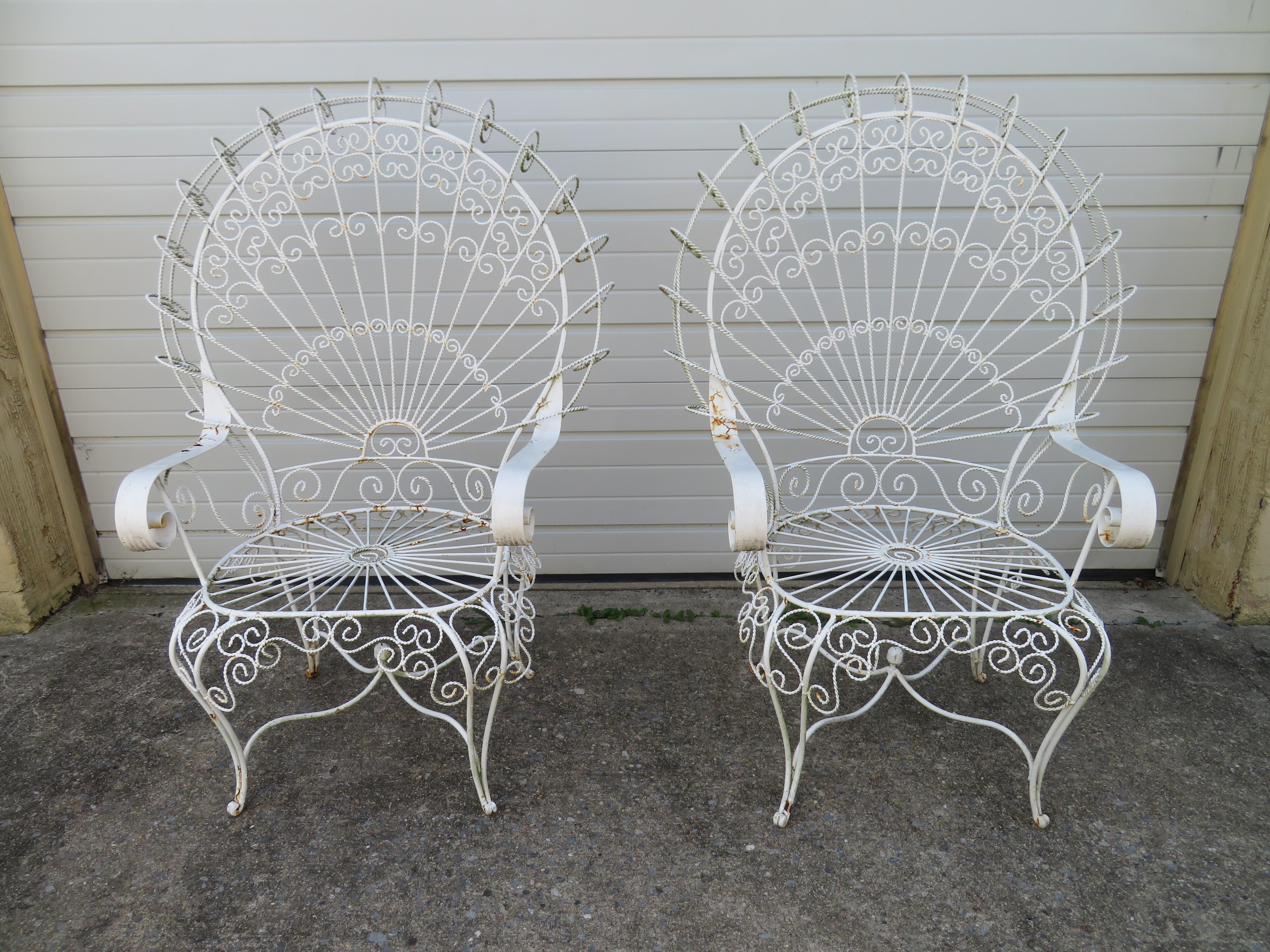 Gorgeous pair of Salterini style ornate wrought iron twisted wire fan back patio chairs. This pair is in vintage condition retaining their original white finish-shows wear to arms. There are no cracks or breaks to the frames-sturdy.