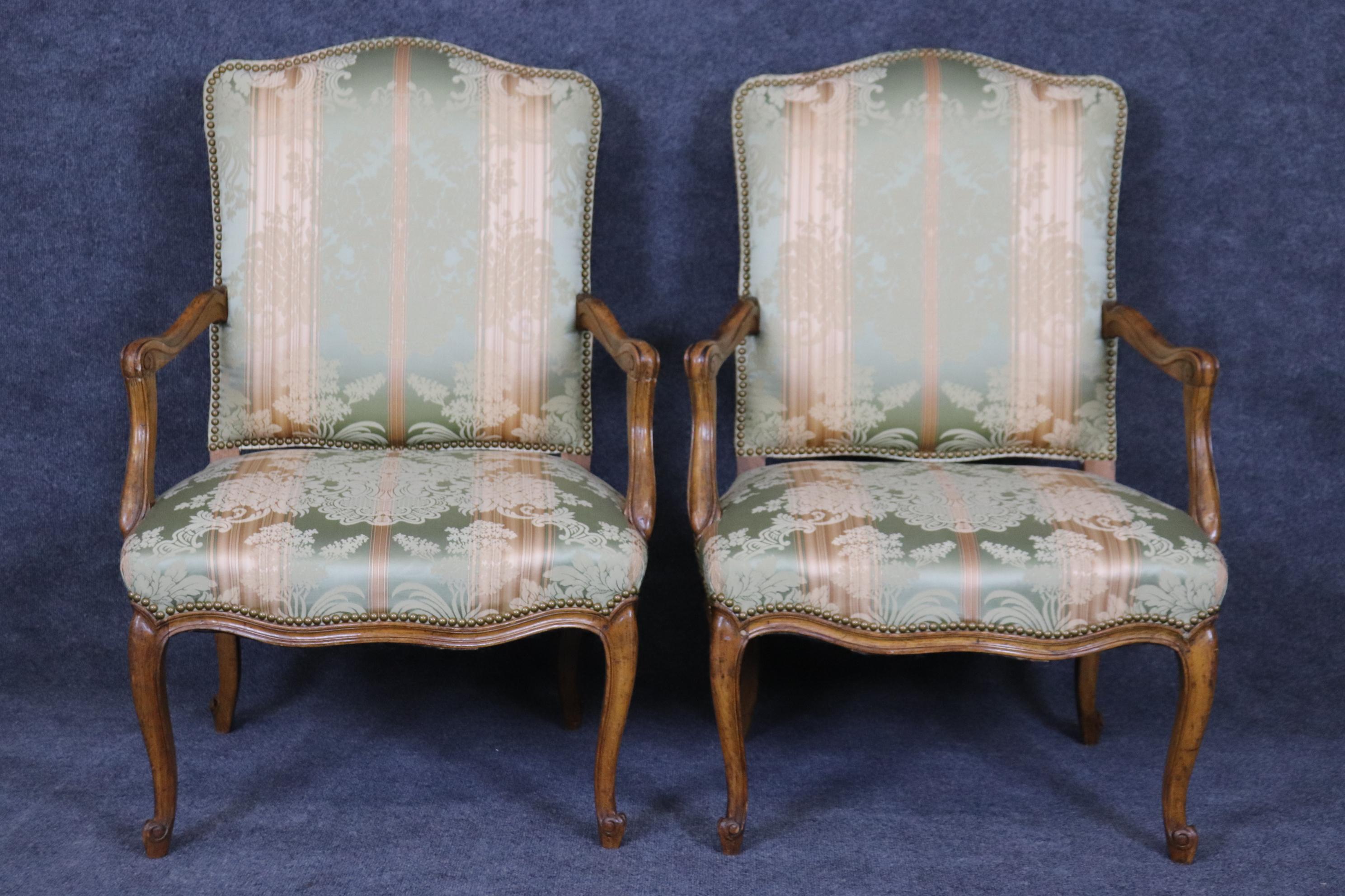 Il s'agit d'une superbe paire de fauteuils de style Louis XV, tapissés de damas de soie et garnis de têtes de clous. Les chaises sont en bon état et très fraîches et propres. Ils ont été utilisés et peuvent donc présenter des taches ou des