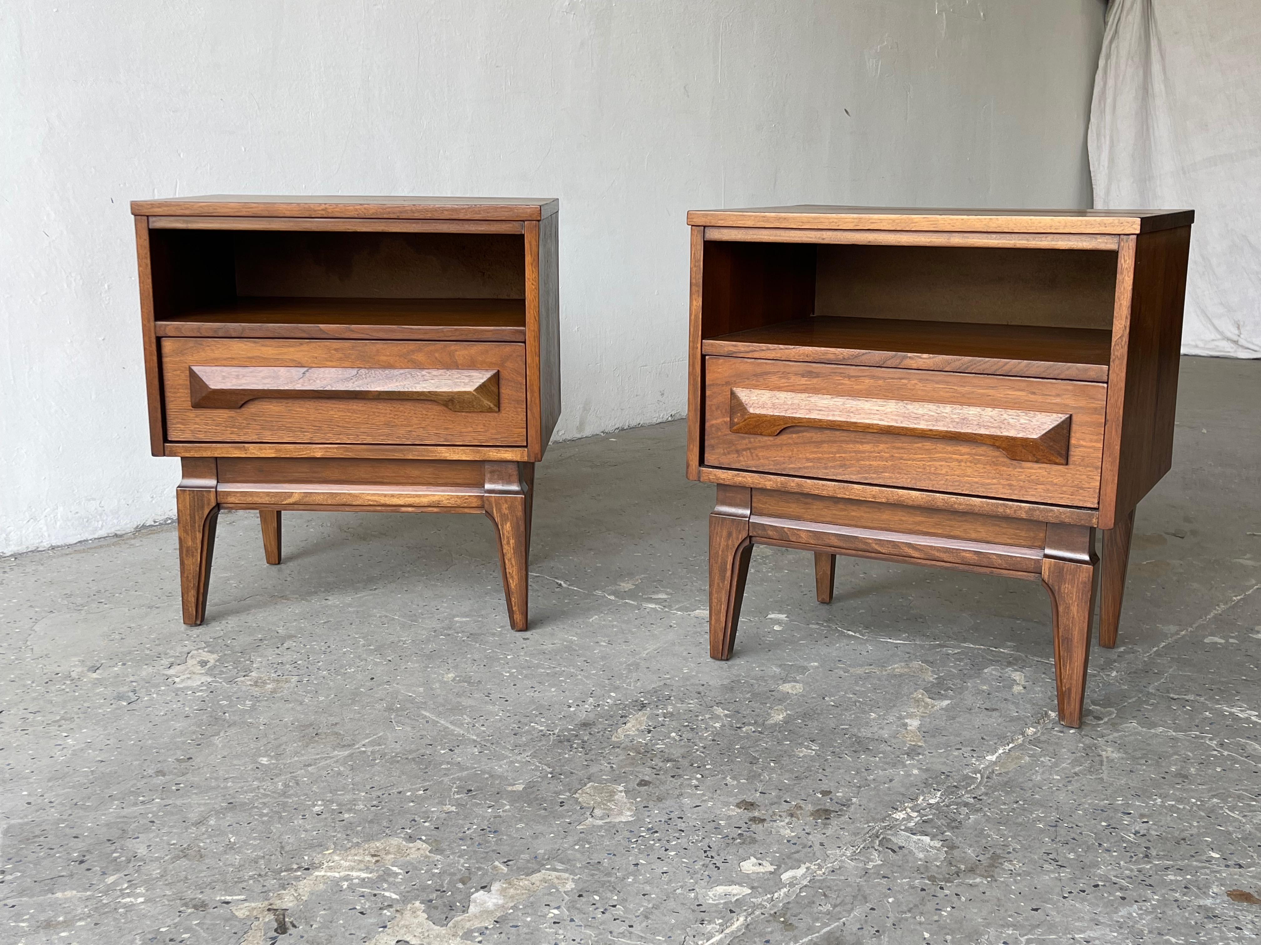 Vintage pair of matching Mid-Century Modern walnut nightstands. Each feature a single drawer with carved wood pulls and open storage space. 

Measures: 21.5