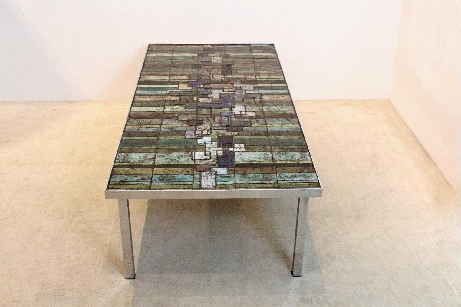 Fantastic brutalist coffee table designed by Pia Manu for Amphora in Belgium, 1970s. The table consists of a Chromed steel base with a Handmade Slate and Ceramic tiled top. The tabletop has a perfect composition composed of inlays of a beautiful