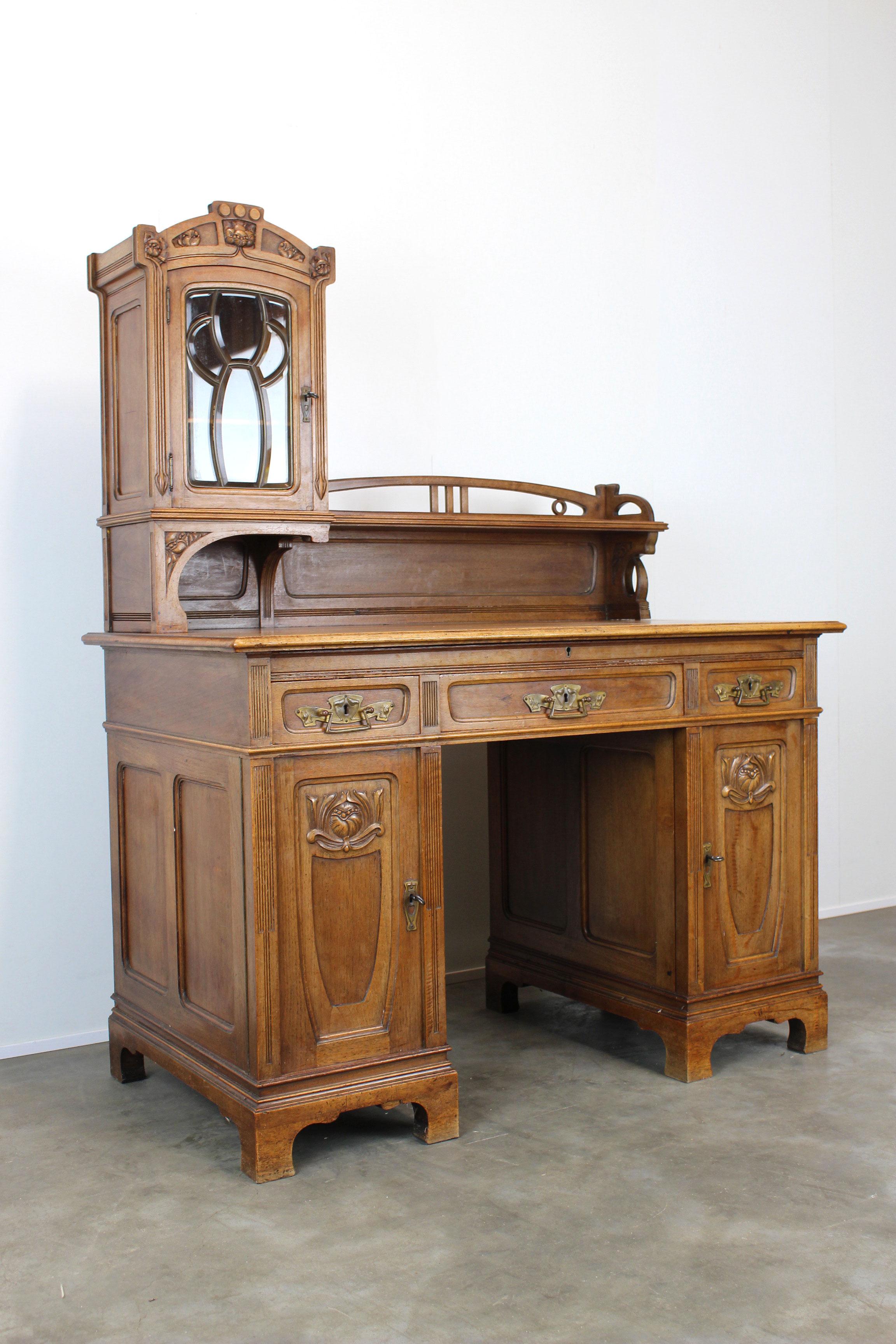 Gorgeous rare small size Art Nouveau / Jugendstil writing desk from 1890s-1900s. 
The desk is made out of solid oak and is fully hand carved with floral motives and organic shapes. 
Stunning details like the beveled glass window and brass floral