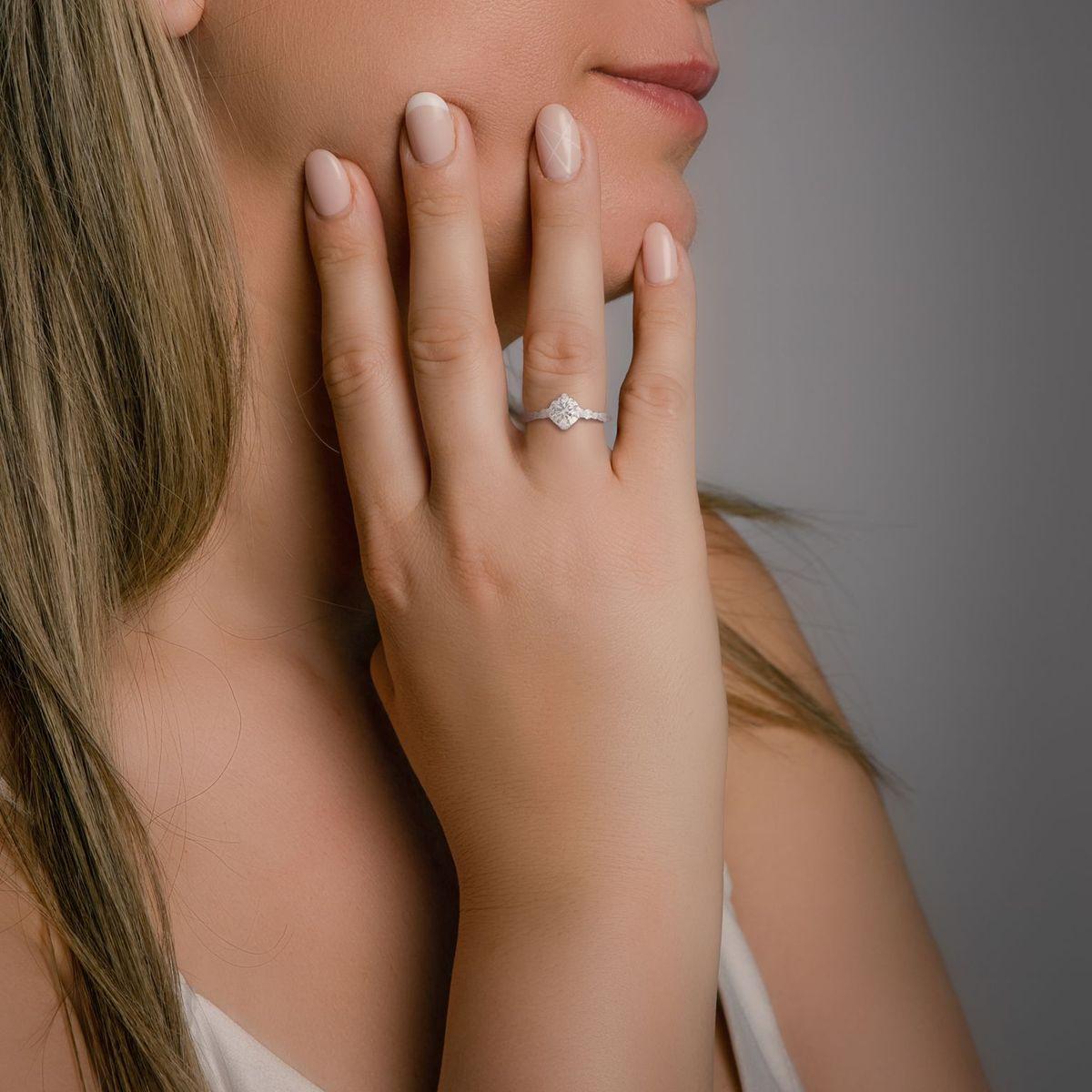 This sophisticated ring, fashioned in 18K white gold, is centered around a dazzling round brilliant natural diamond. The diamond, known for its remarkable sparkle and fire, is graded F in color, indicating a high level of whiteness and brightness.