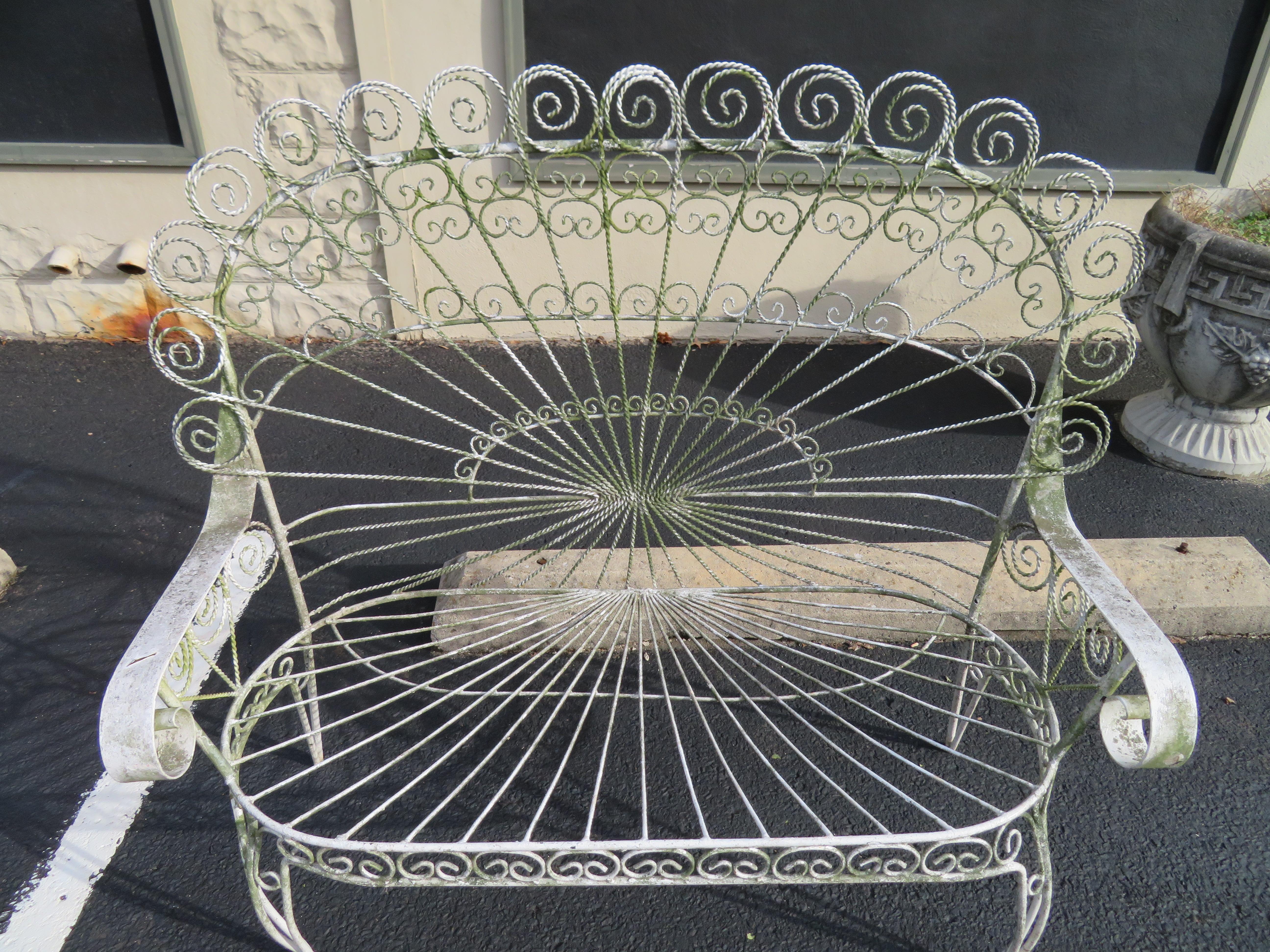 Gorgeous Salterini style ornate wrought iron twisted wire fan back patio bench. This piece is in vintage condition retaining it's original white finish with a lovely green lichen patina. There are no cracks or breaks to the frame-sturdy.
