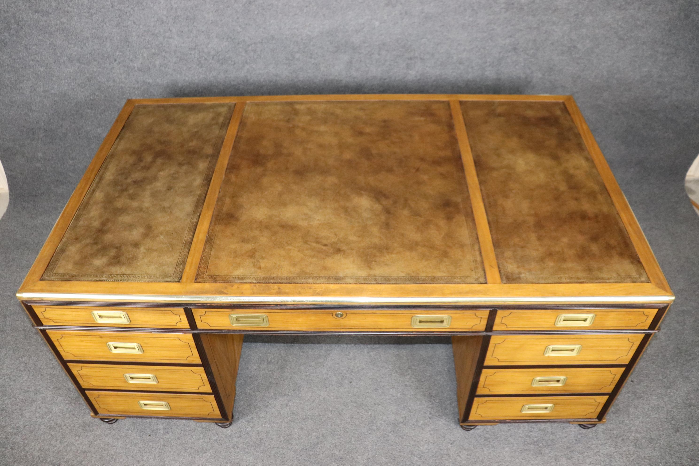This is a spectacular executive desk with gorgeous brass, dark mahogany and satinwood. The desk features two doors on one side with cabinets and a bank of drawers and keys for the locks on the front side. The desk is absolutely stunning. Measures 72