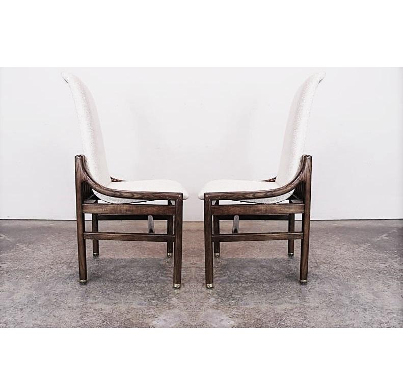 Mid-Century Modern sculptural dining chairs by Henredon. Consisting of two armchairs and six side chairs. Chairs feature floating frames fully restored in a dark walnut stain, brass feet caps and covered in beautiful white upholstery. They are well