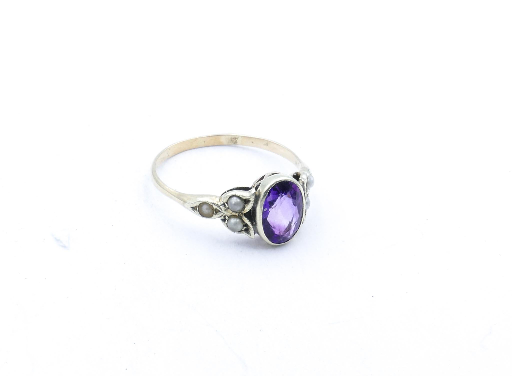 This lovely old Ring is just so very feminine.
An old deeply hued Amethyst forms the centrepiece with 3 Seed Pearls placed in a triangular scalloped fashion on either side  It is set in 9ct White Gold.
A pretty pretty Sweetheart of a Ring.
