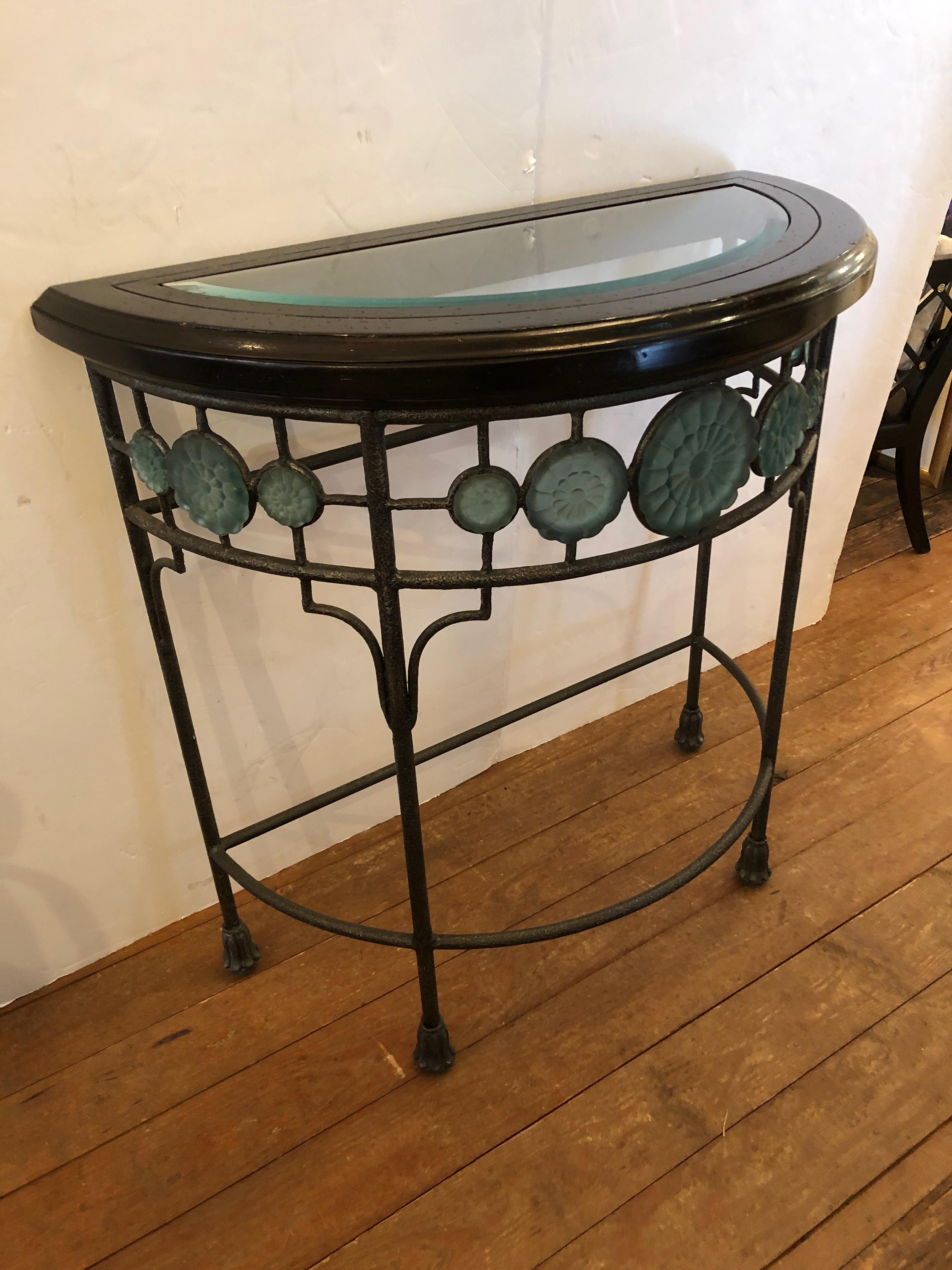 Beautiful medium sized demilune console table having wood framed half moon top with beveled glass surface and handsome wrought iron base. The semi circle beneath the top is adorned with gorgeous cut glass celadon green rosettes.