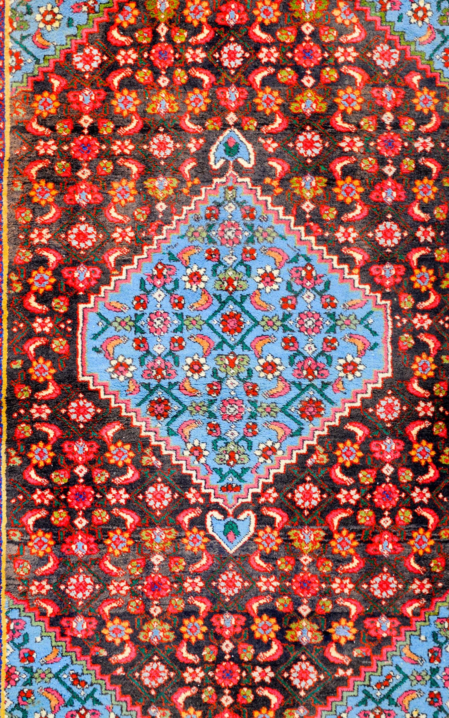 A gorgeous vintage mid-20th century Persian Hamadan rug with a light blue diamond medallion with a floral and leaf trellis pattern, on a similar floral and leaf trellis patterned field on a black ground. The border is exceptional with a bold floral