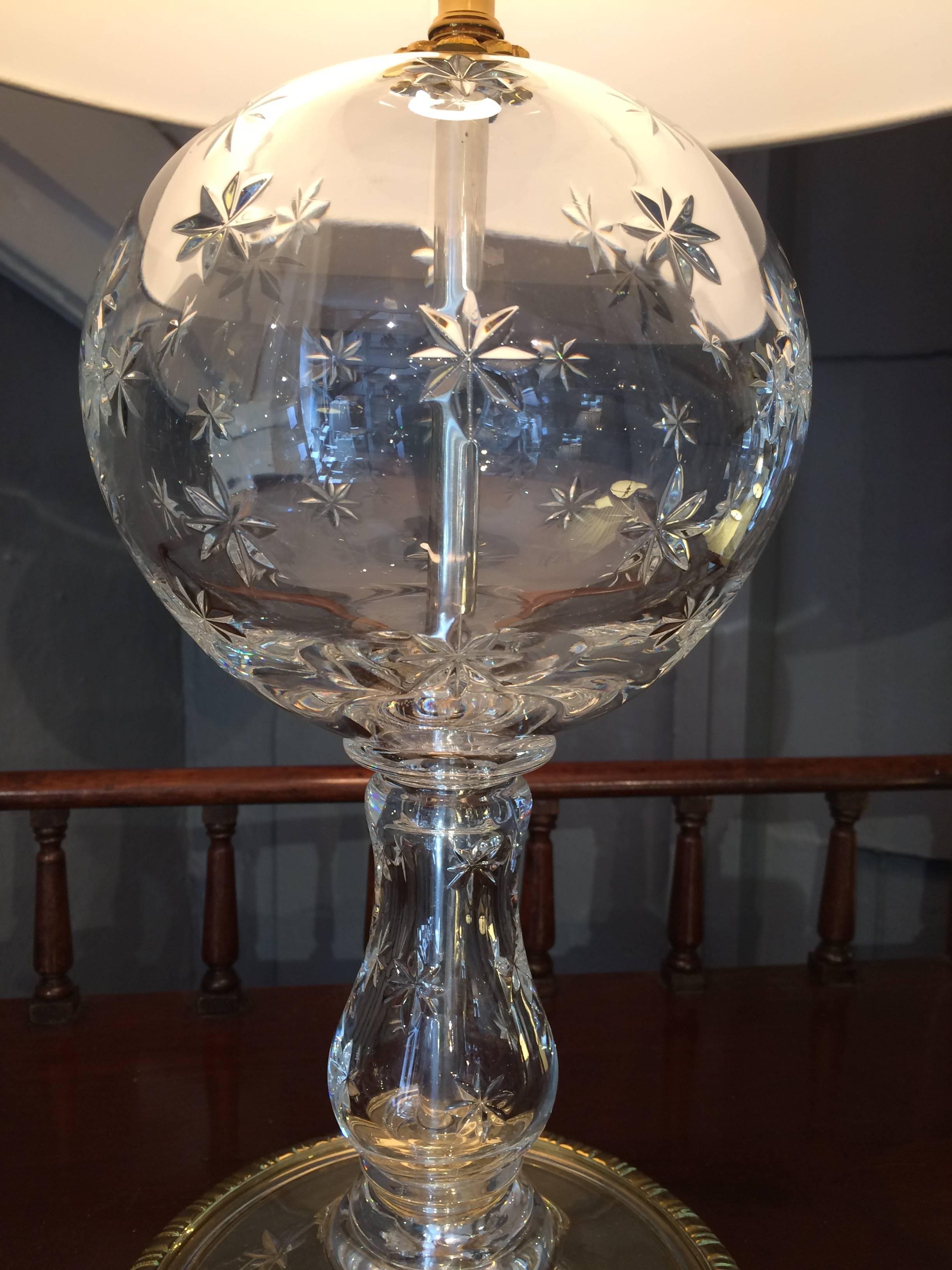 Lovely table lamp having a crystal globe shaped base with star motife and brass frame on the bottom. Base is 7 inches diameter.