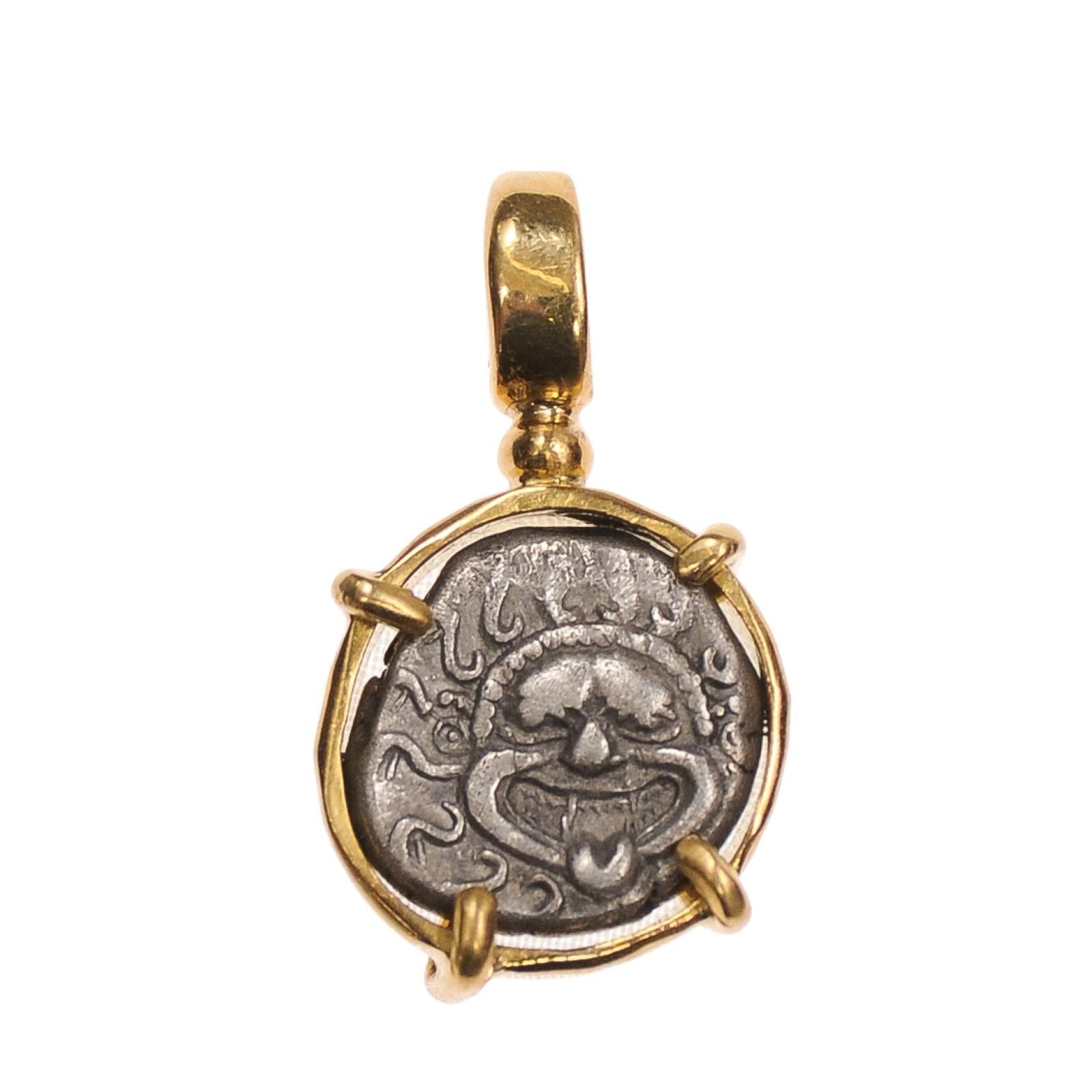 Colgante [moneda] de dracma de gorgona y ancla engastado en oro de 18 quilates. La dracma fue una de las primeras monedas del mundo. Su nombre deriva del verbo griego que significa 