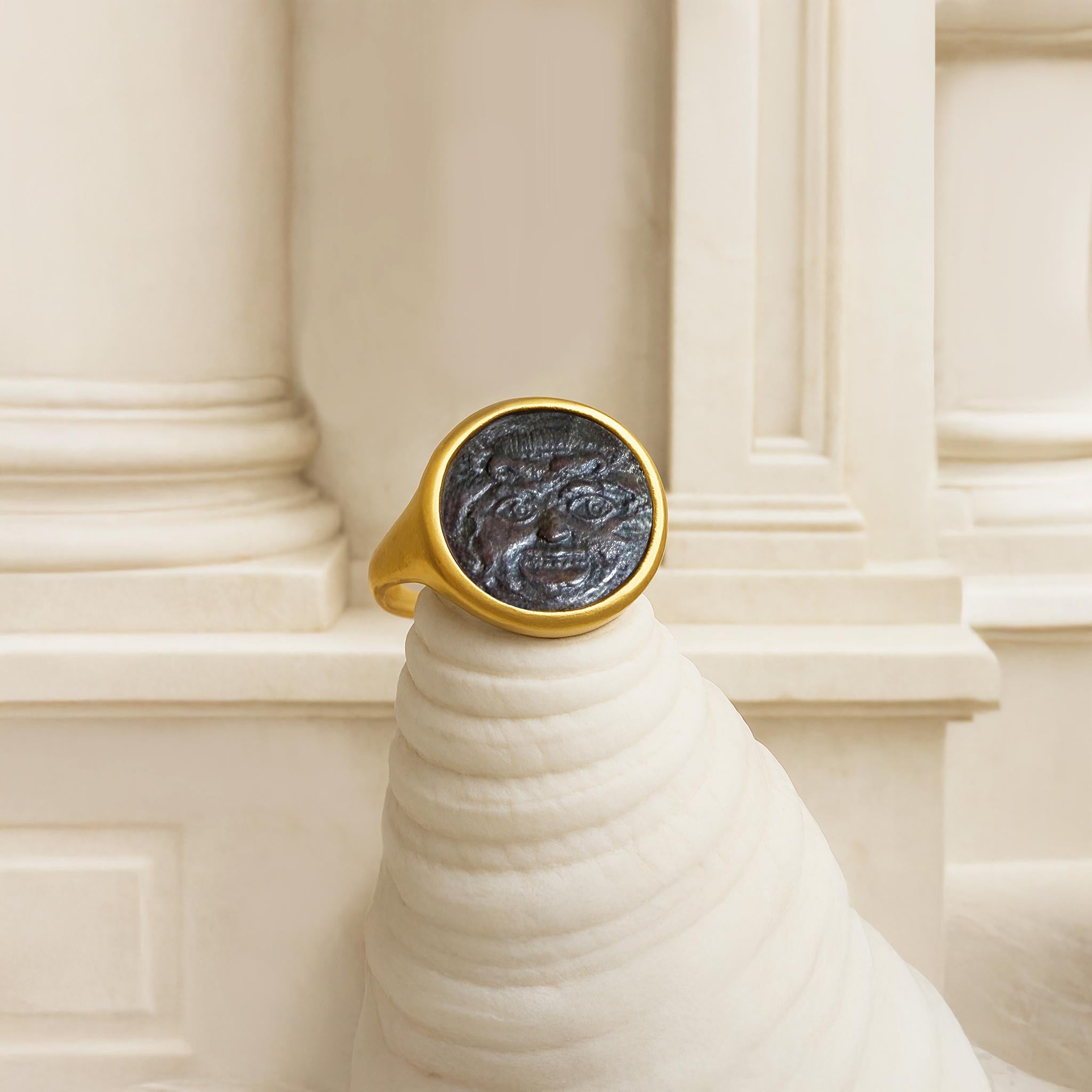 Cette exquise bague en or 18 carats est ornée d'une authentique pièce de monnaie grecque en bronze datant de 420-405 av. J.-C., ornée d'une représentation saisissante de la Gorgone, une figure mythique ancrée dans la tradition antique.

Les