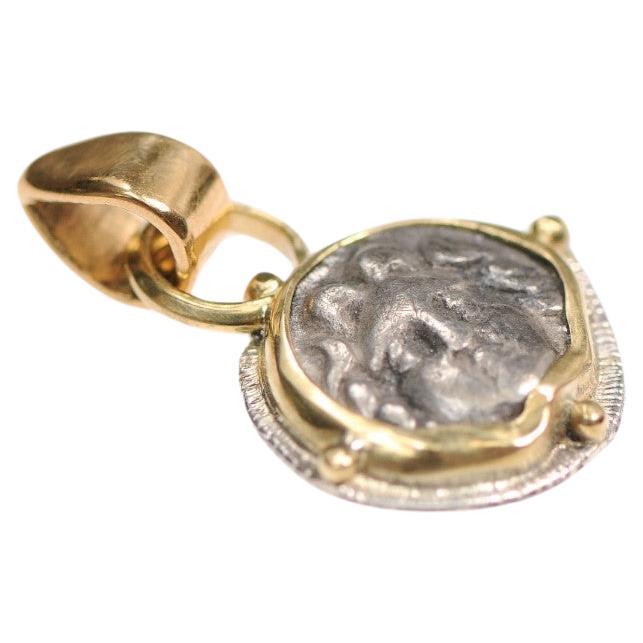 Un ciondolo Obolo AR rivolto verso la Gorgonia e rifinito con oro 22k e argento sterling. L'origine di questo Obolo AR è la Pisidia, Selge, circa 350-300 a.C.. La moneta originale misura 11 mm di diametro e pesa 0,80 grammi. Questo angelico e