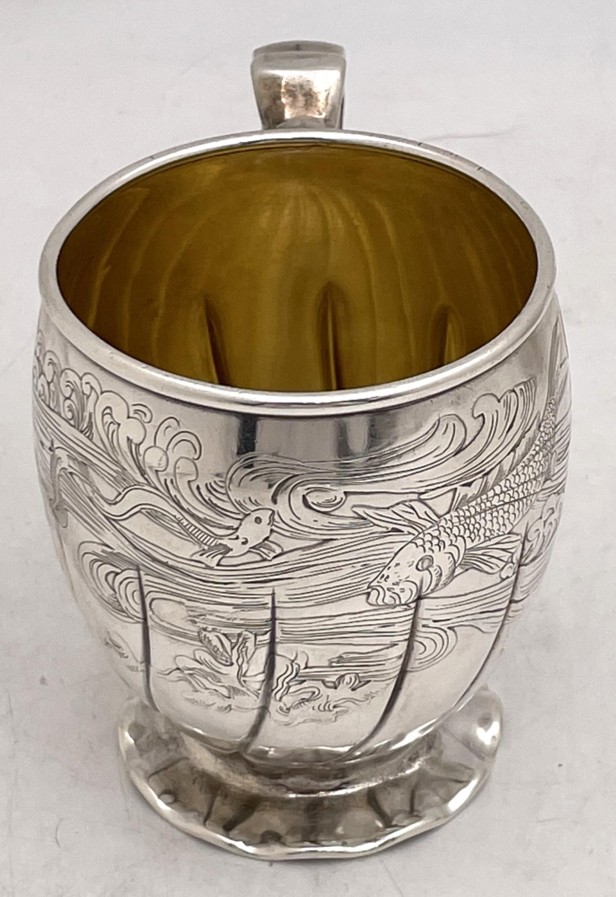 Gorham special order sterling silver child's or christening mug, made around 1880, gilt inside, adorned with acid-etched motifs including fish and waves, and in an elegant, curvilinear design. It measures 3 3/4'' in height by 2 7/8'' in diameter at