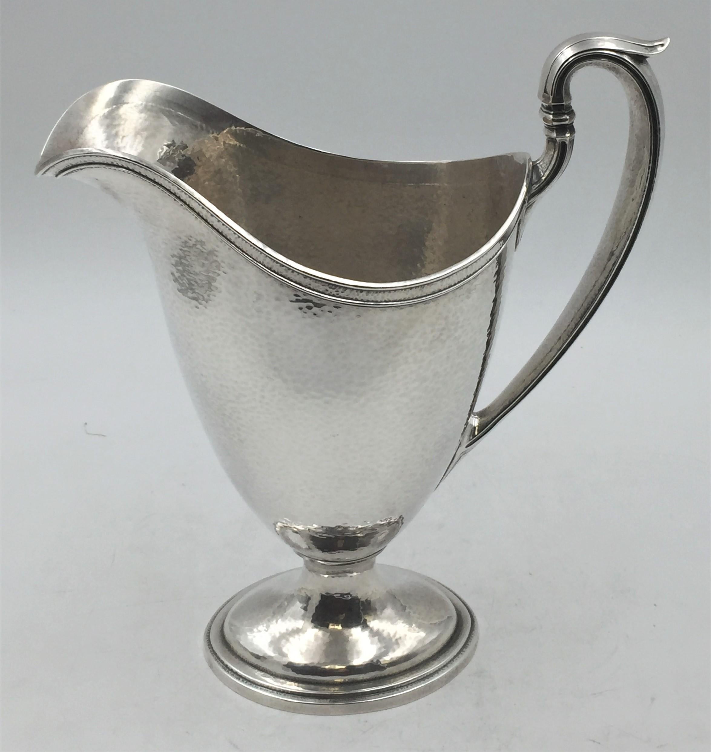 Gorham sterling silver pitcher, beautifully hand hammered, from 1919 in geometrically-inclined, Art Deco style with an applied handle. It measures 11 1/2'' in height by 9 3/4'' from handle to spout by 5'' in width, weighs 26.1 ozt, and bears