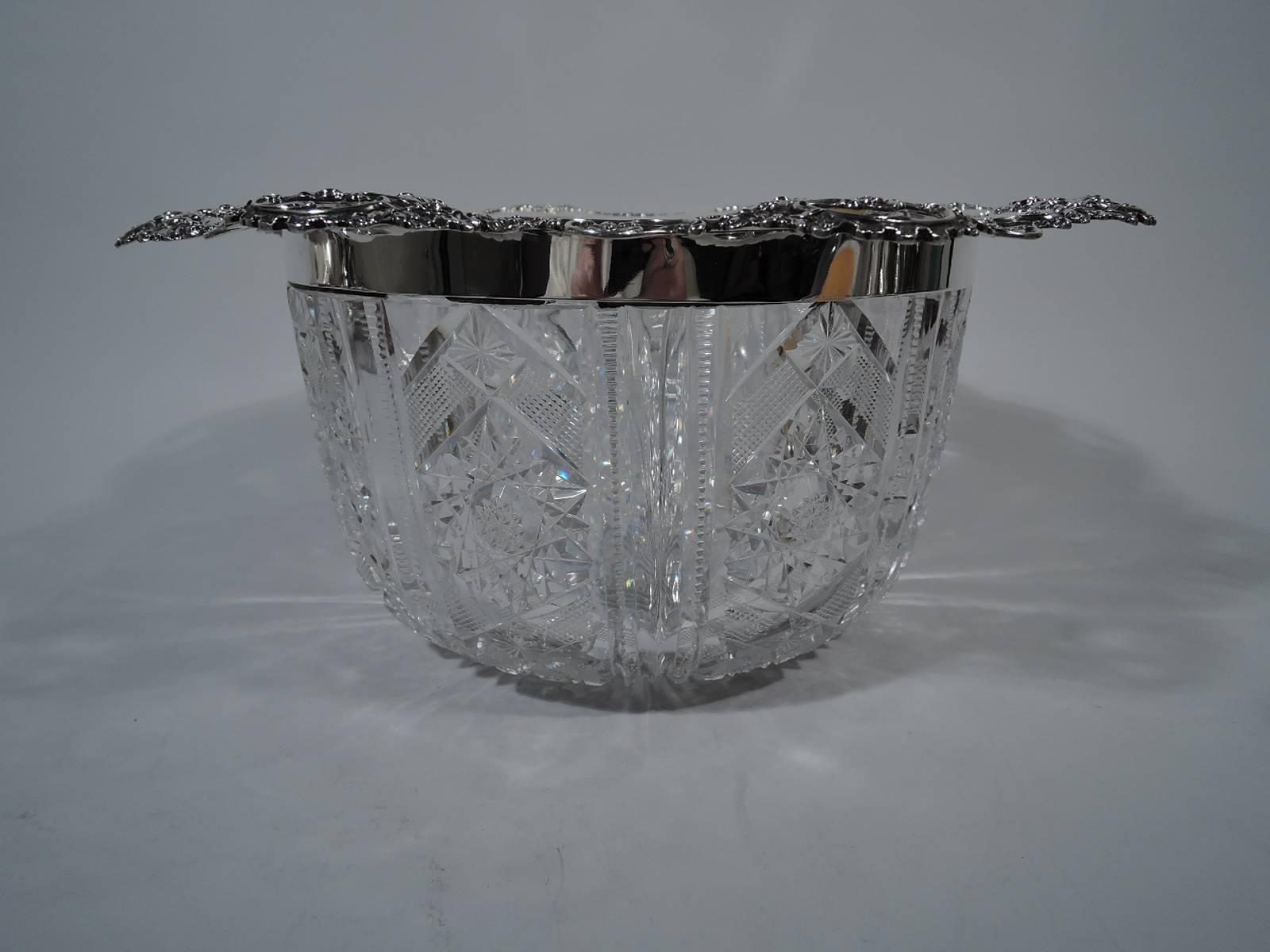 Fancy sterling silver and brilliant-cut-glass centrepiece bowl. Made by Gorham in Providence in 1899. Clear glass bowl with curved sides and diaper and star ornament between notched pilasters. Open and scrolled sterling silver rim with applied