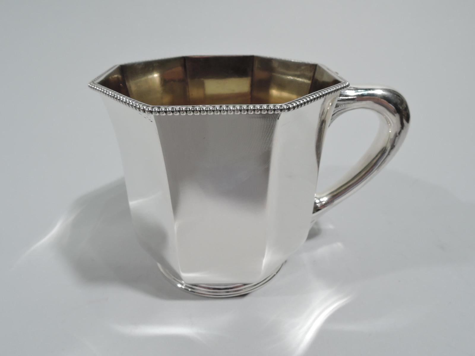 Edwardian Modern sterling silver baby cup. Made by Gorham in Providence in 1895. Octagonal bowl and short round foot; leaf-mounted handle. Beaded rim and gilt-washed interior. Unusual form in the emerging geometric style. Fully marked including