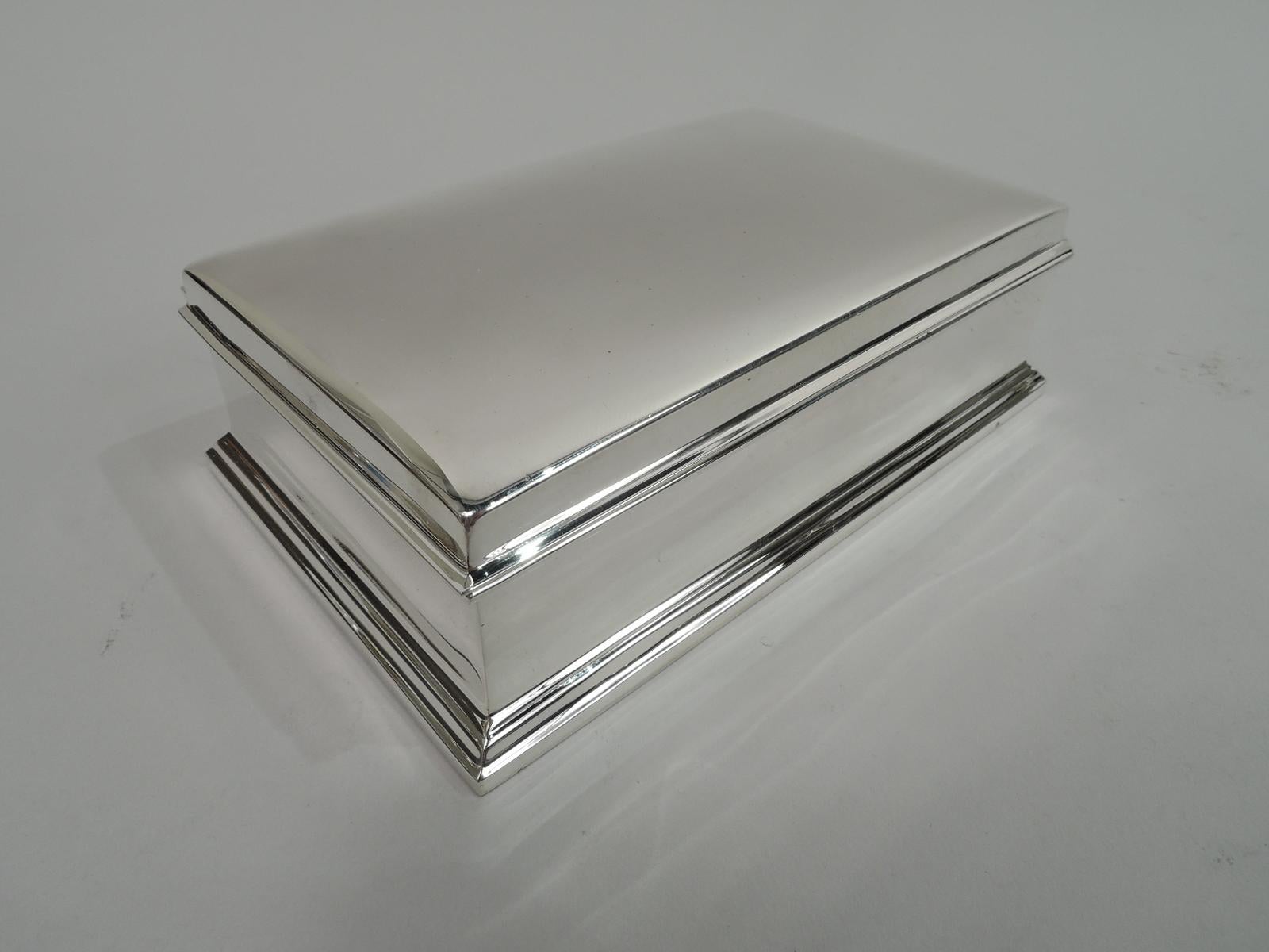 Modern sterling silver box. Made by Gorham in Providence, ca 1940. Rectangular with straight sides and spread and stepped base. Cover hinged with gently curved top and wraparound overhanging rim. Box interior cedar lined. Cover interior gilt washed.