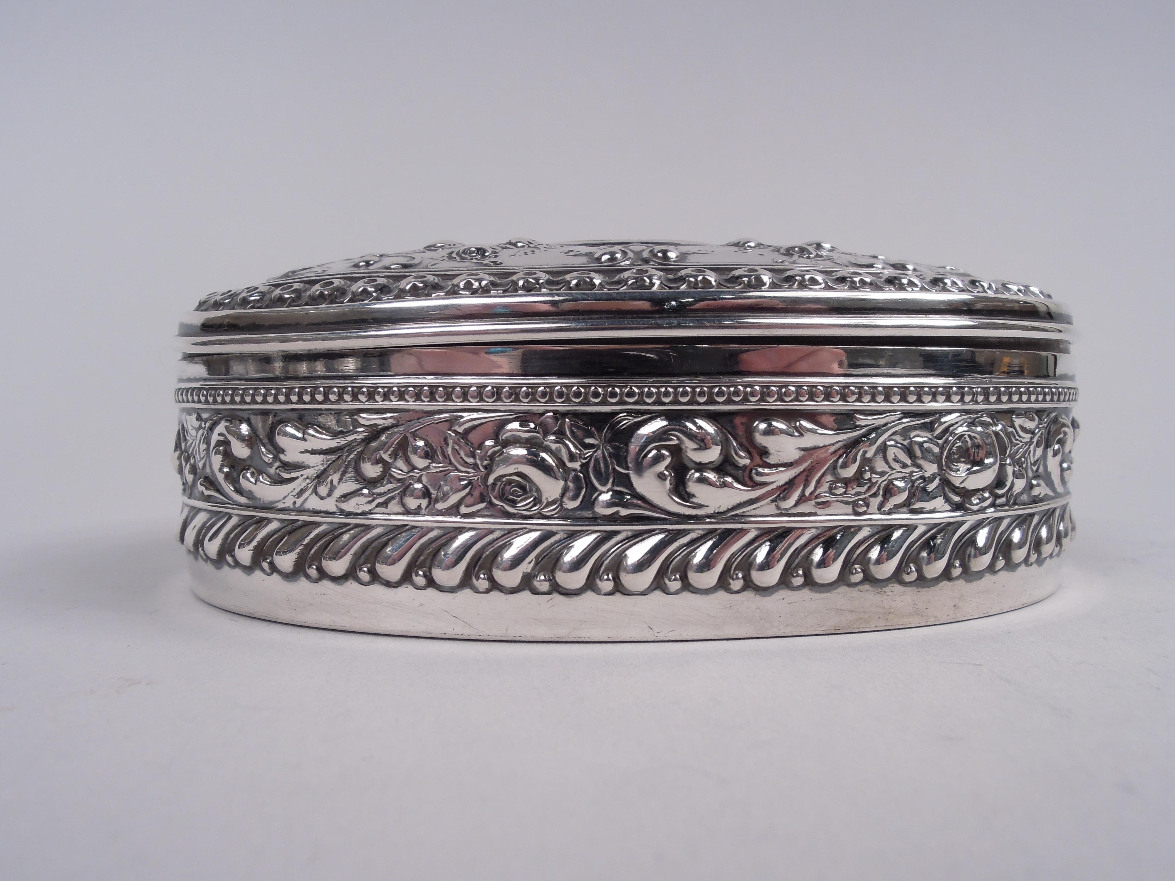 Victorian Classical sterling silver jewelry box. Made by Gorham in Providence in 1897. Oval with hinged cover. Chased leafing scrollwork, flowers, and scallop shells. Beaded and guilloche borders. Cover top has central oval (vacant). Velvet lining