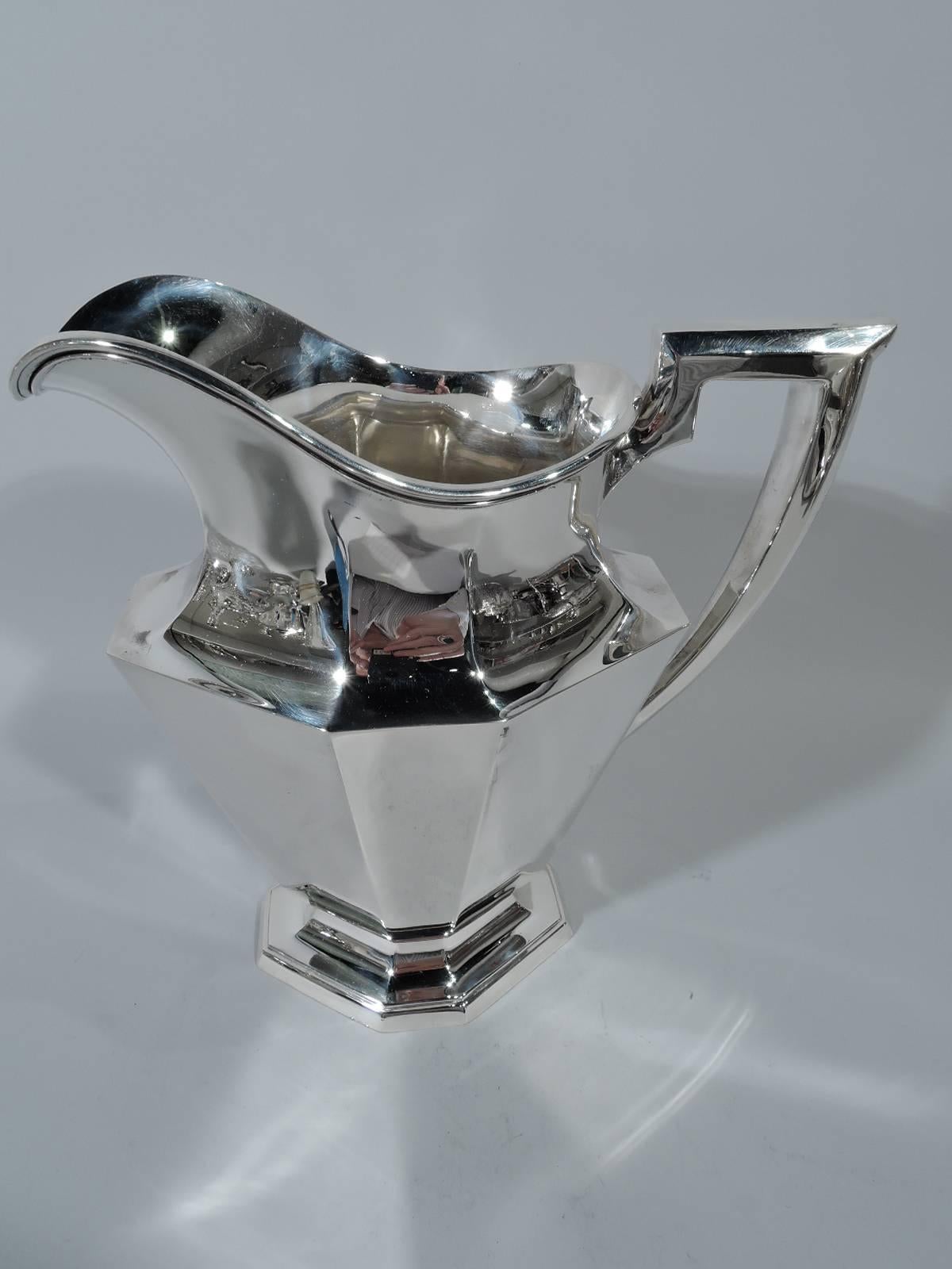 Art Deco sterling silver water pitcher. Made by Gorham in Providence in 1920. Tapering sides with alternating wide and narrow facets, foot same, scrolled bracket handle, and helmet mouth. Hallmark includes date symbol, no. A9716, and volume (3