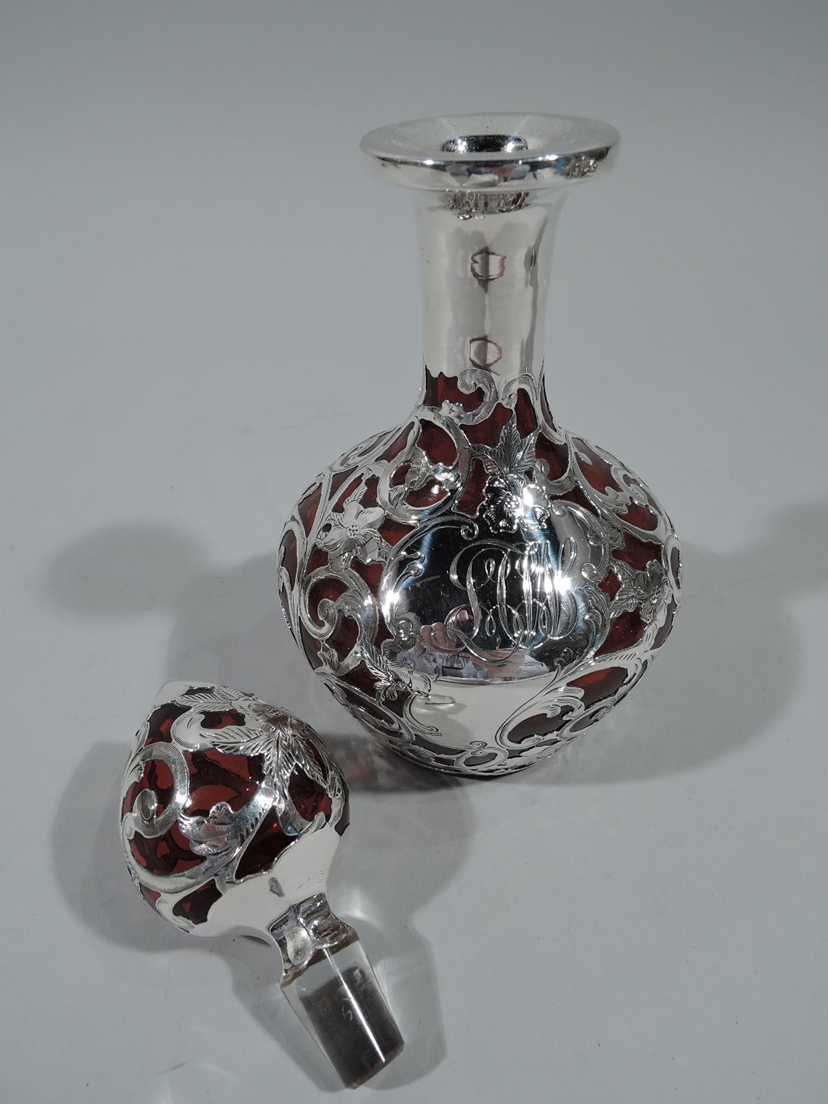Art Nouveau cranberry glass perfume with silver overlay. Made by Gorham in Providence, ca 1890. Ovoid bottle, cylindrical neck, and everted rim. Ovoid stopper with faceted base and short clear glass plug. Overlay in form of dense pell-mell