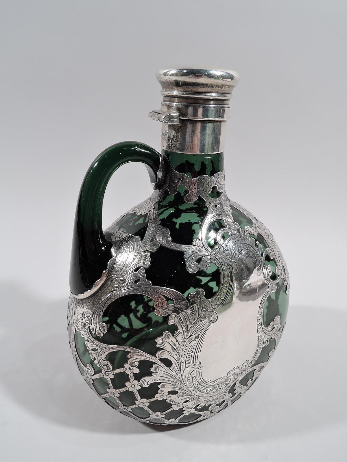 Turn-of-the-century Art Nouveau glass jug decanter with silver overlay. Made by Gorham in Providence. Round with flat front and back; neck cylindrical with sterling silver collar and hinged and cork-lined cover. Loose and meandering leafy scrolls,