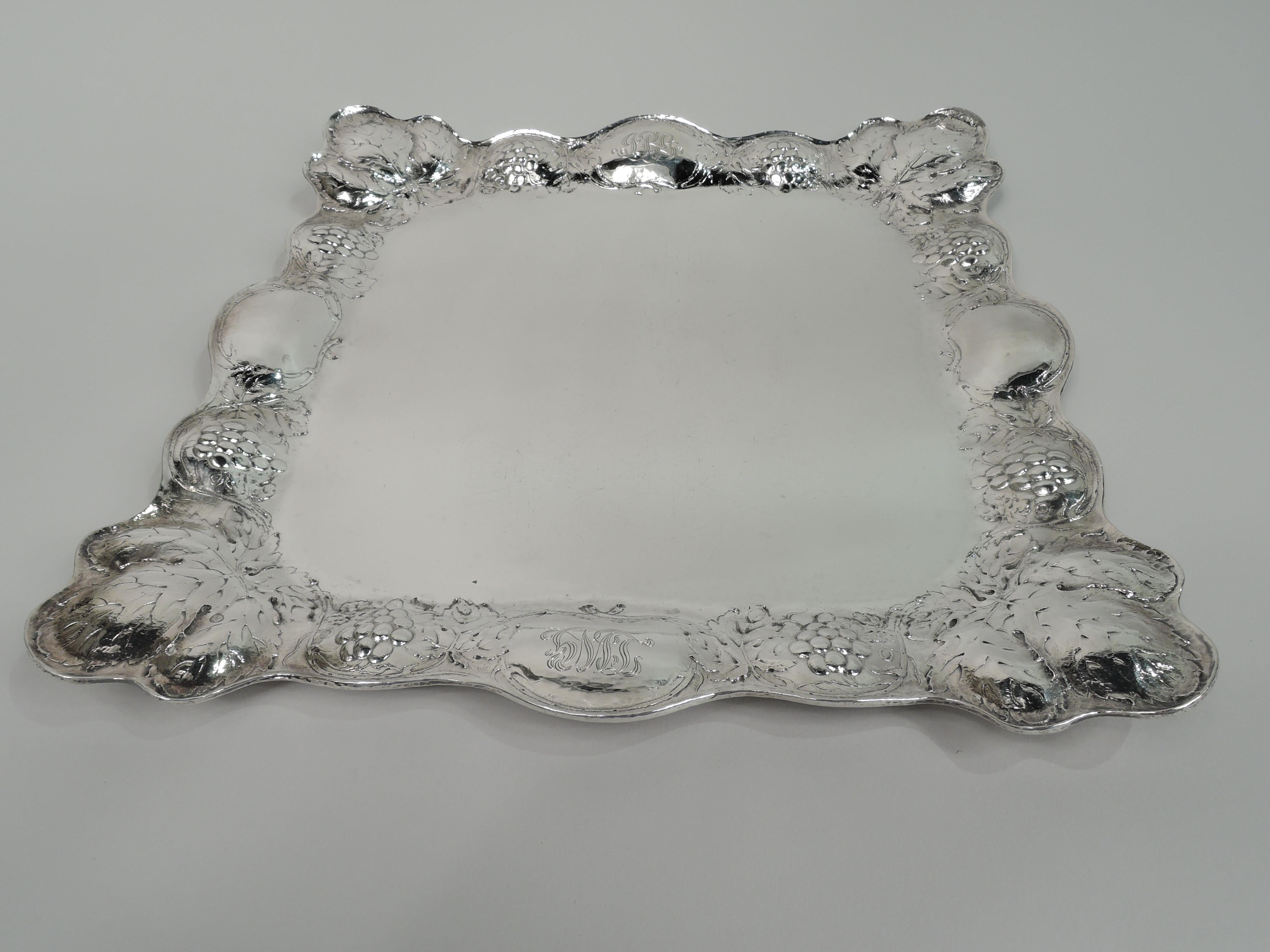 Art Nouveau Martelé silver tray. Made by Gorham in Providence on November 11, 1899. Square well with curved corners. Lobed and tapering sides with scalloped rim. Chased meandering fruiting grapevine and large leaves at corners on hand-hammered