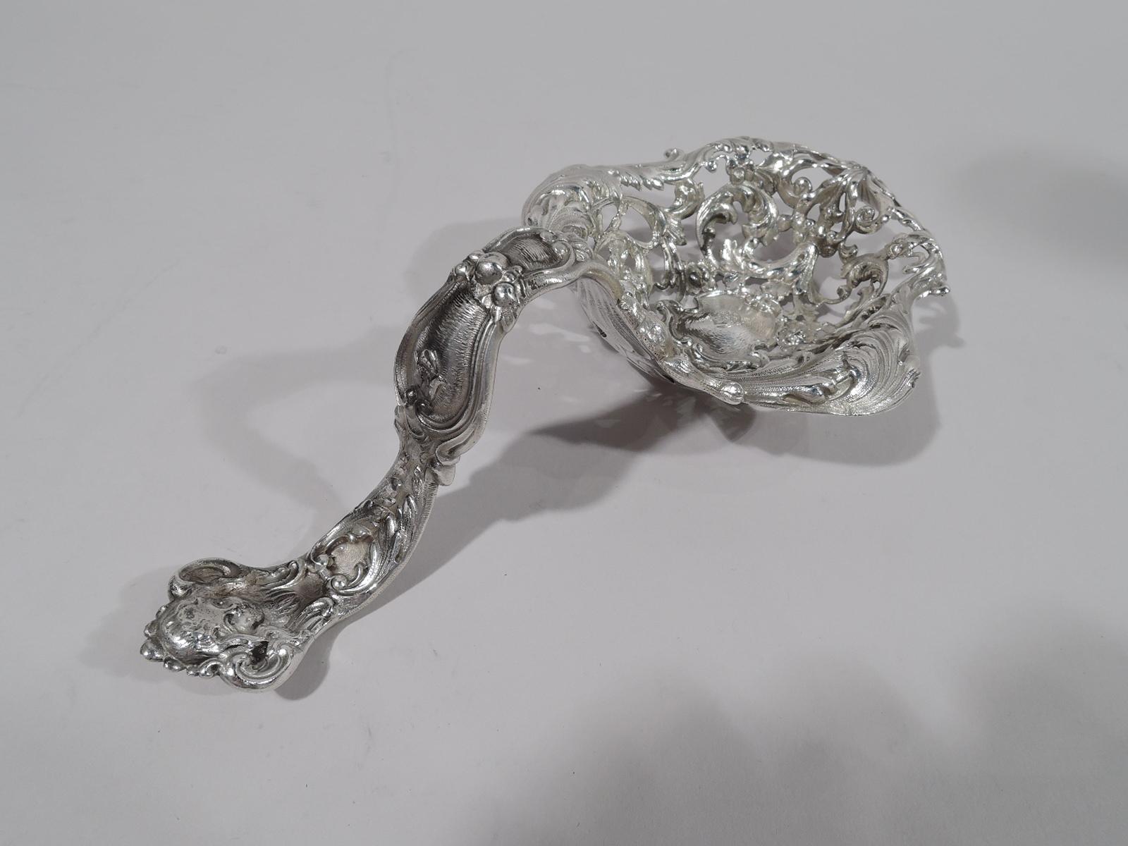 Art Nouveau Rococo sterling silver bonbon scoop. Made by Gorham in Providence in 1899. Deep and shaped bowl with turned-down rim, and pierced scrolls, flowers, and angel heads. Central strapwork cartouche engraved with monogram. Wavy baluster handle