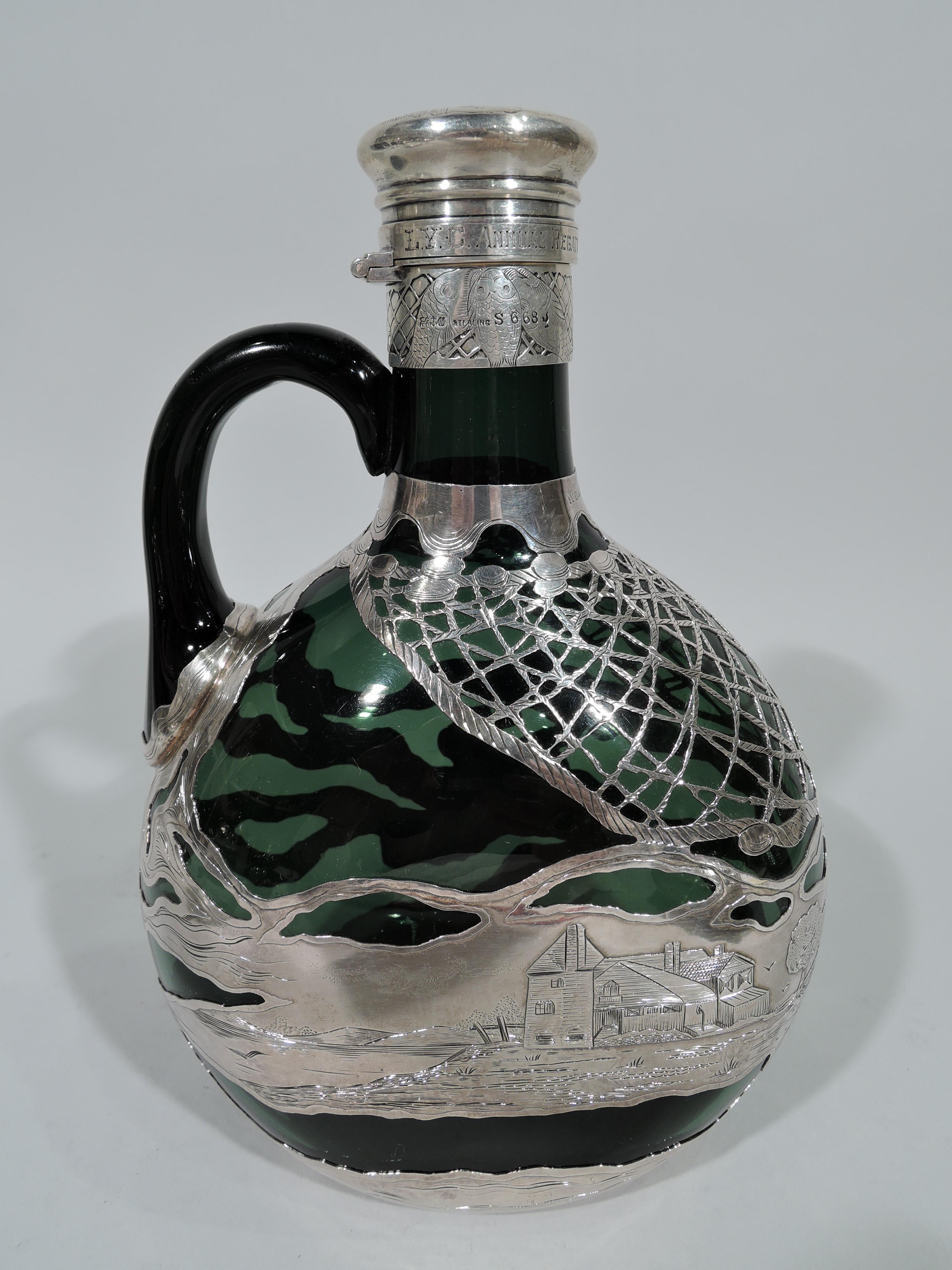 Art Nouveau emerald glass decanter with engraved and acid-etched pictorial silver overlay. Made by Gorham in Providence in 1890. Round and flat body with cylindrical neck and scroll handle mounted to neck and body. Overlay depicts landscape with