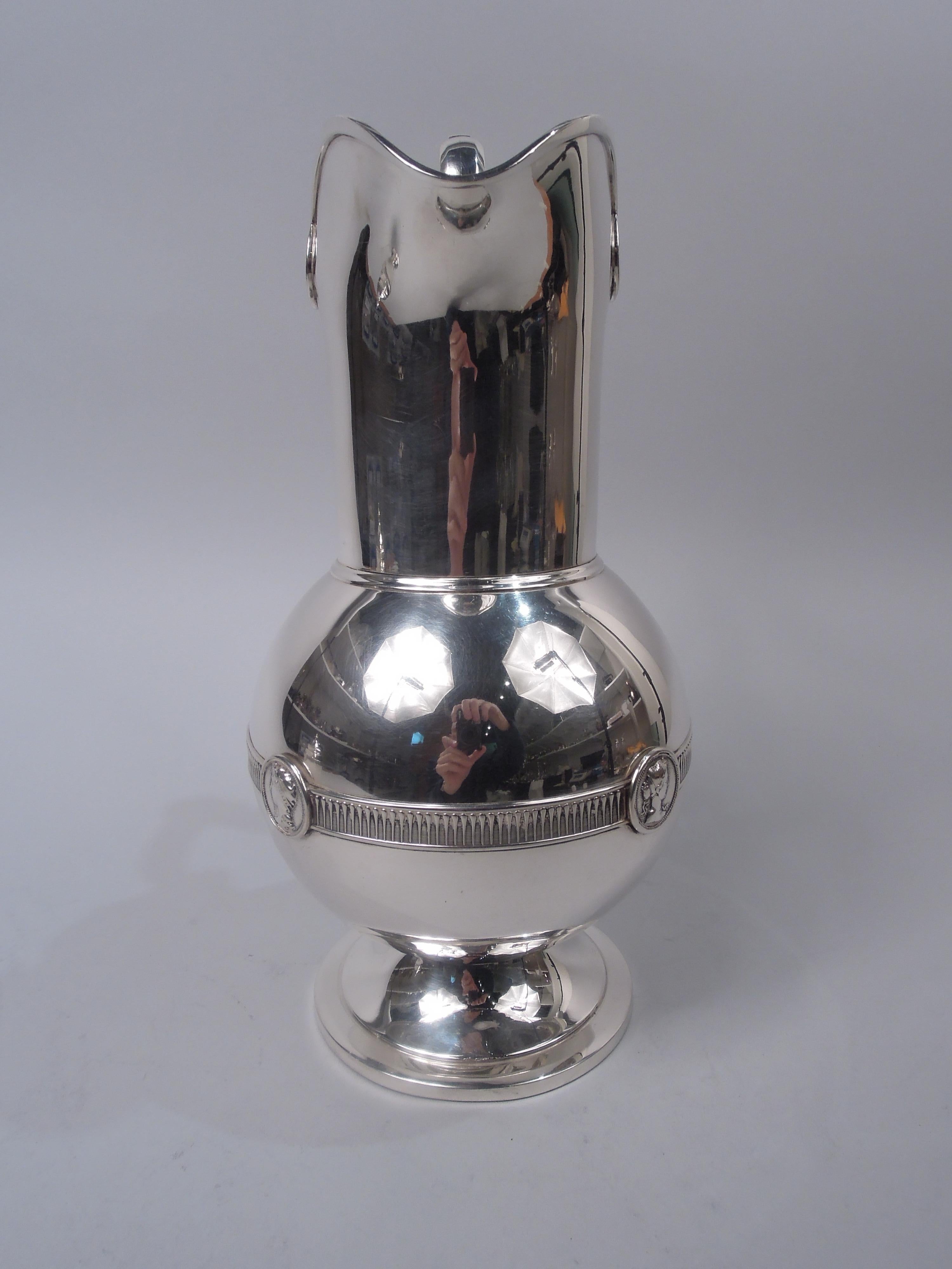 Medallion coin silver water pitcher. Made by Gorham in Providence, ca 1860. Globular bowl on raised and stepped foot; tall straight neck and helmet mouth. Straight and high-looping handle; scroll cap with Classical female rondel profile and entwined