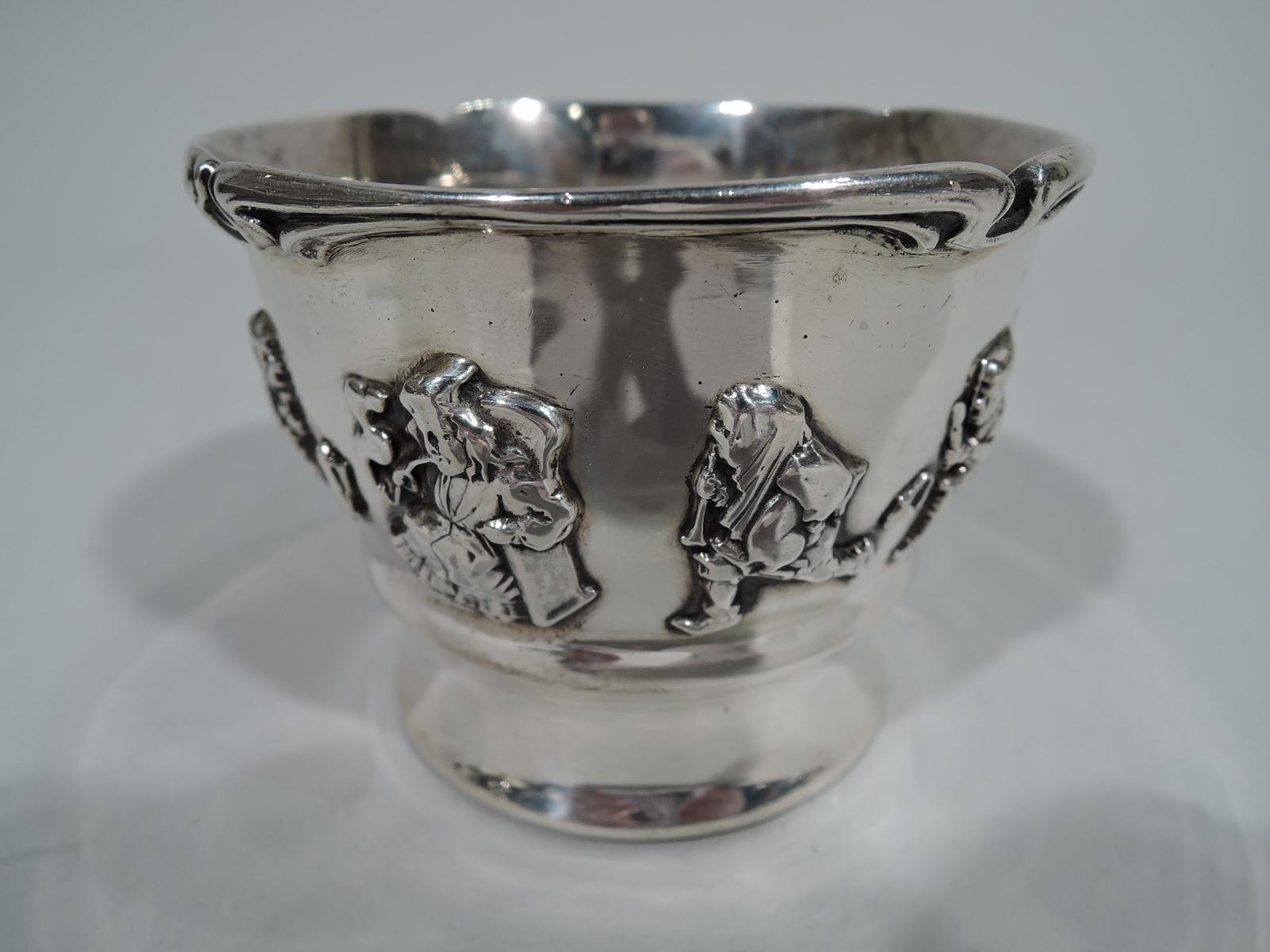 Edwardian sterling silver baby cup with applied allegorical frieze. Made by Gorham in Providence. Concave foot, c-scroll handle, and scrolled whiplash rim. The stages of man, from eager urchin to placid pipe-smoking gent, encircle the body. Fully