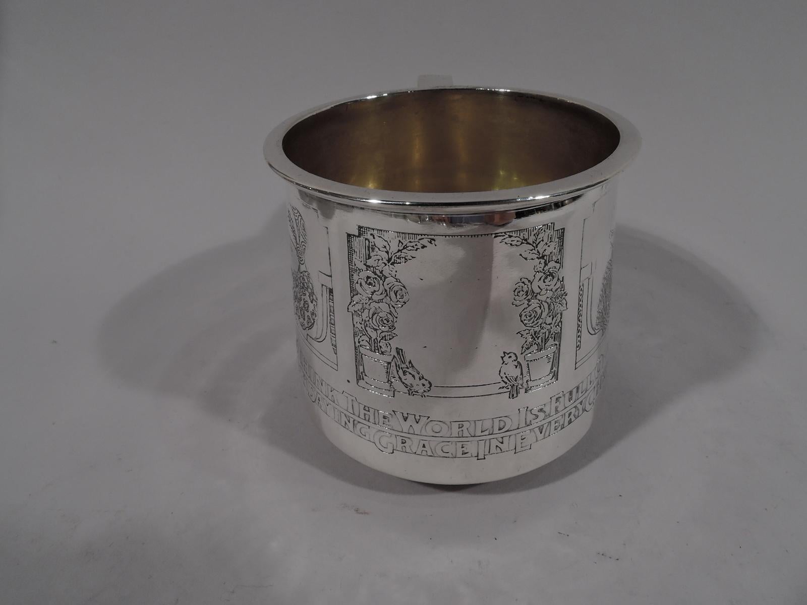 Edwardian Sterling silver baby cup. Made by Gorham in Providence, circa 1910. Gently upwards tapering sides, scrolled bracket handle, and flat rim. Gilt-washed interior. Two acid-etched frames with little girls from around the world (each in
