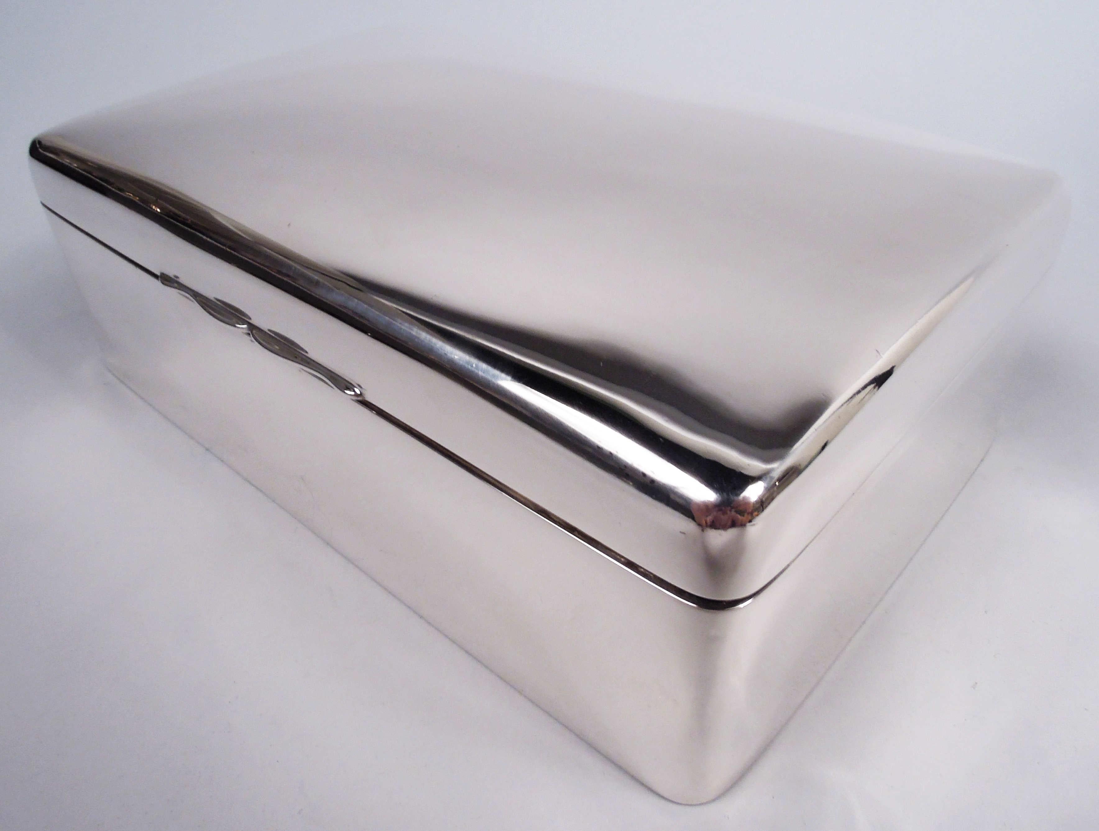 Edwardian Modern sterling silver box. Made by Gorham Manufacturing Co. in Birmingham in 1912. Rectangular with straight sides and curved corners. Cover hinged with curved top and scrolled tab. Box interior cedar-lined and partitioned. Underside felt