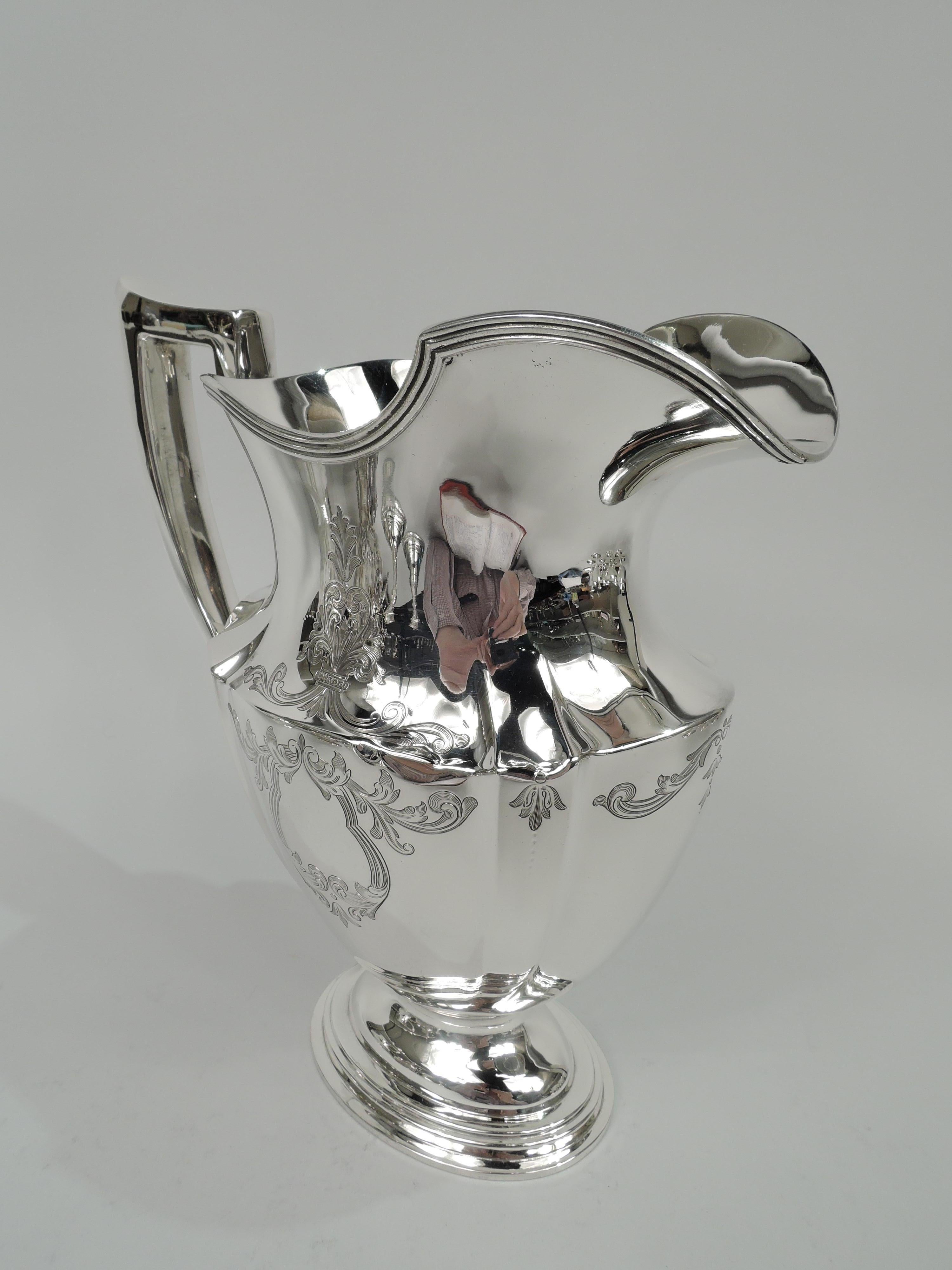 Engraved Plymouth sterling silver water pitcher. Made by Gorham in Providence in 1911. Tapering and paneled ovoid body, reeded helmet mouth, capped scroll bracket handle, and stepped oval foot. Leafing scrollwork and two cartouches (vacant). Fully