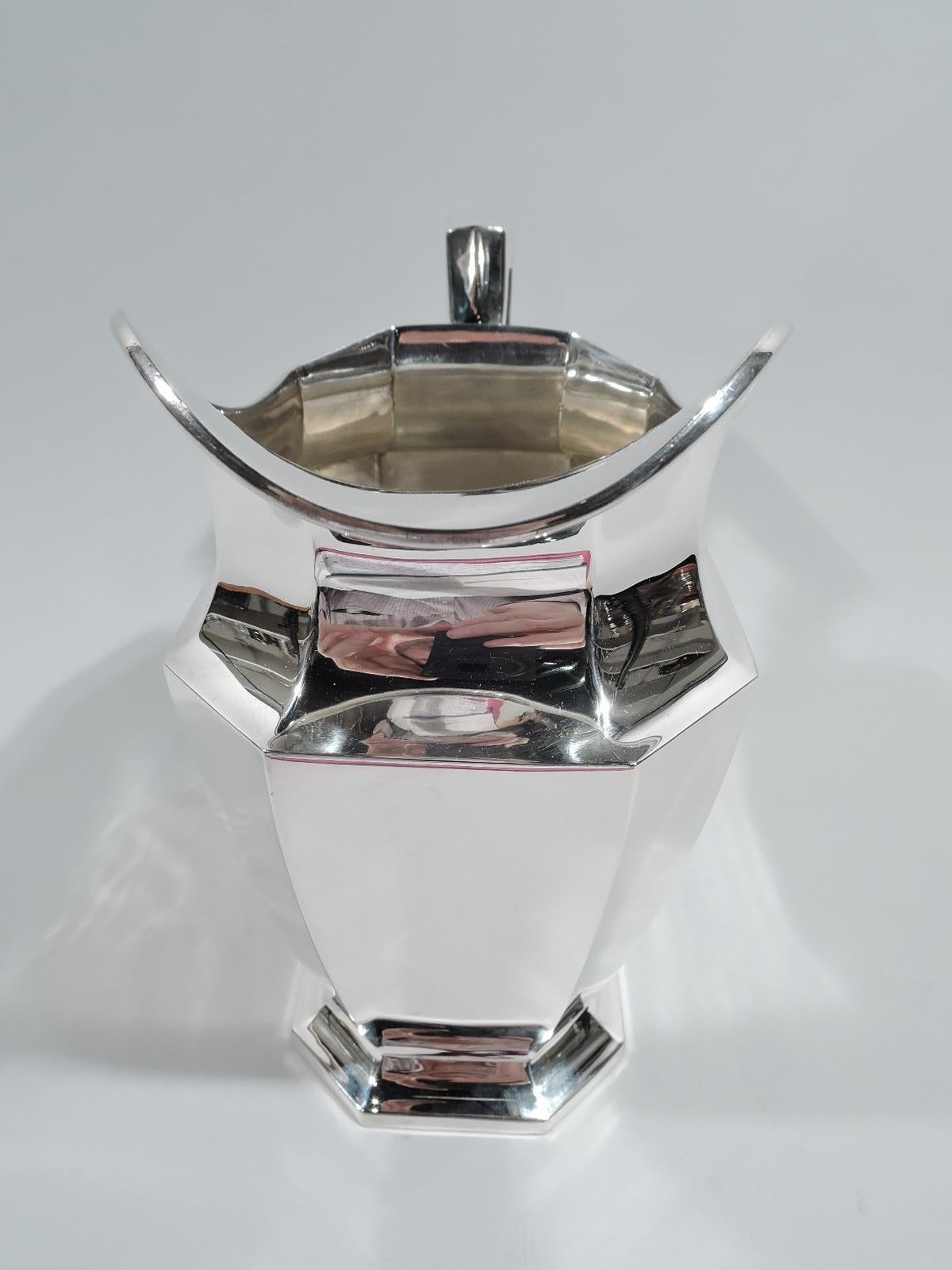 Fairfax sterling silver water pitcher. Made by Durgin (part of Gorham) in Concord, New Hampshire, ca 1920. Faceted with rectilinear body and raised foot, and helmet mouth. Scroll-bracket handle. A desirable piece in the classic Art Deco pattern.
