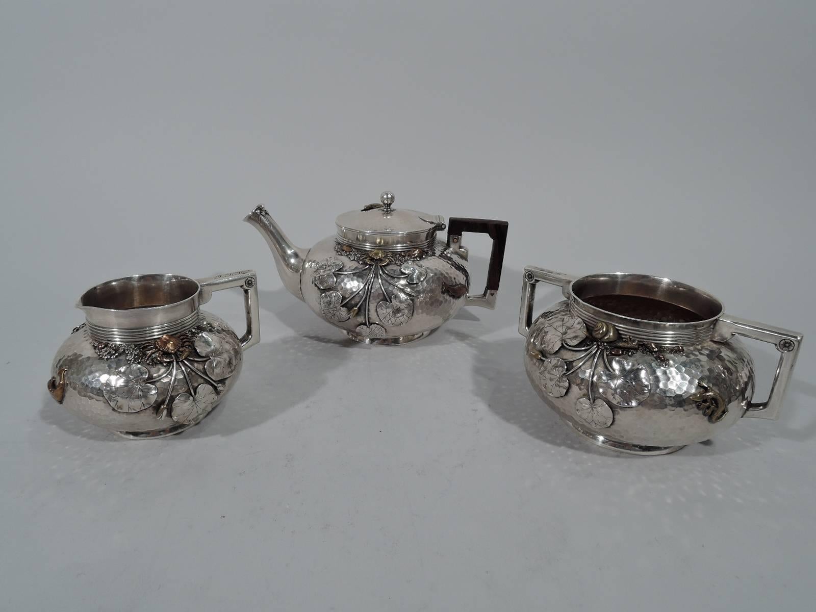 Japonesque sterling silver and mixed metal tea set. Made by Gorham in Providence in 1879-1880. This set comprises teapot, creamer, and sugar.

Each: Bellied with short reeded neck and foot ring. Bracket handles (teapot handle stained wood). Teapot