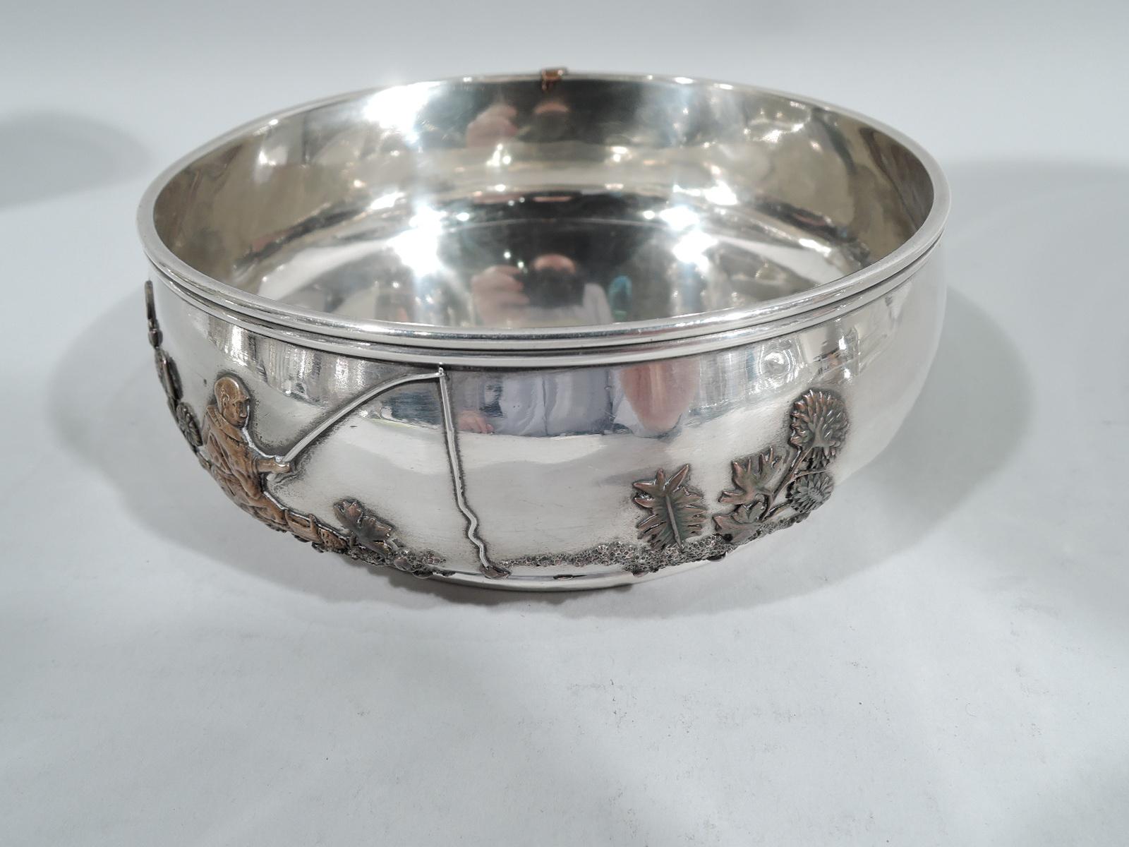 Japonesque mixed metal on sterling silver bowl. Made by Gorham in Providence in 1881. Curved sides, molded rim, and foot rim. On exterior are applied vegetation rooted in granulated soil, a stray dragonfly, and solitary fisherman who has hooked a