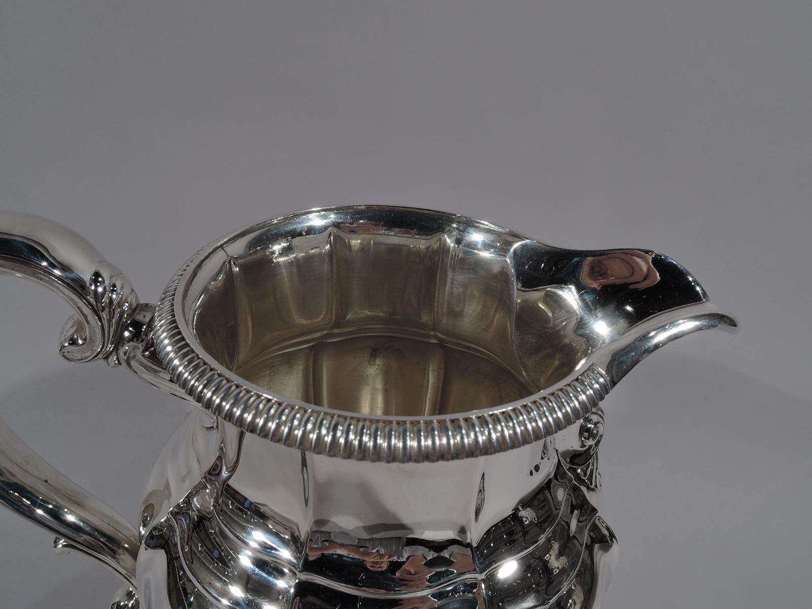 Modern classical sterling silver water pitchers made by Gorham in Providence, circa 1930. Lobed baluster body, U-spout with scallop shell at base, capped scroll handle, and raised foot. Gadrooning. Fully marked including no. 531/1 and volume (4 7/8