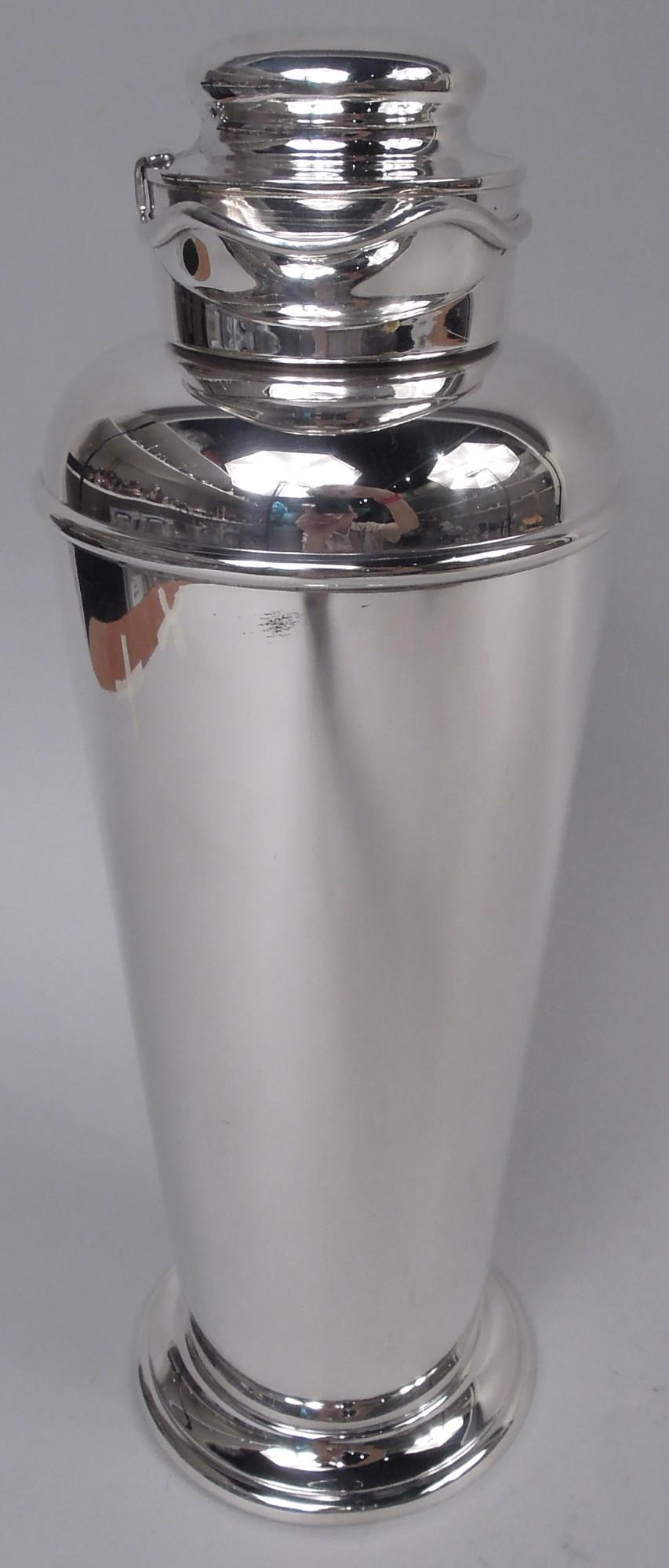 Prohibition-era sterling silver cocktail shaker. Made by Gorham in Providence in 1930. Tall and tapering bowl with curved shoulder. Short neck with helmet mouth; cover domed with ice guard. Cover scroll bracket and spread foot. Holds 4 pints of