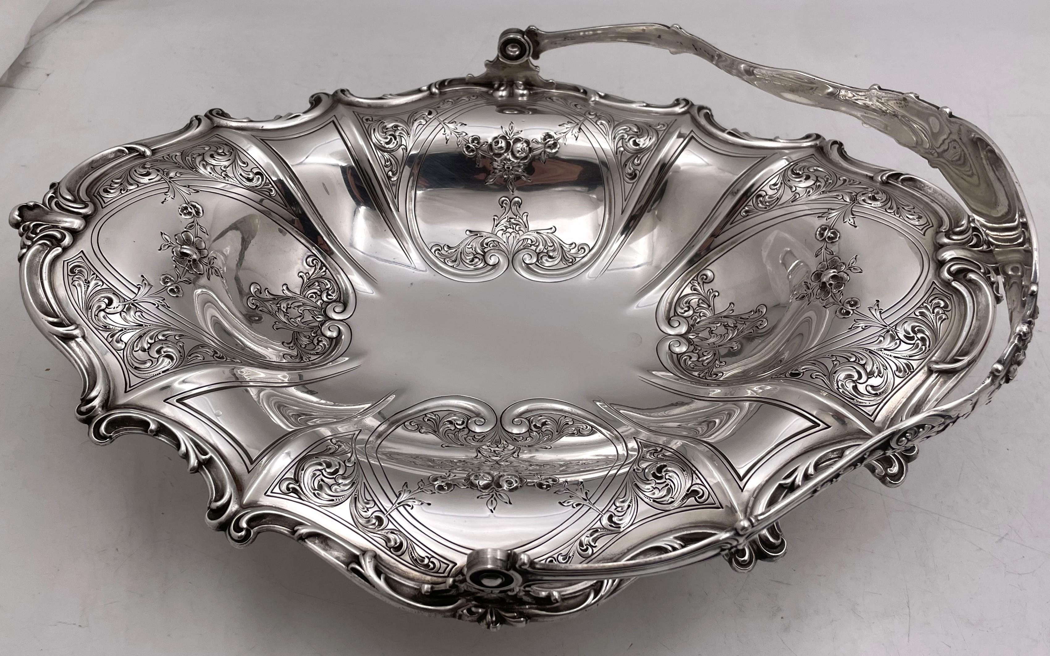Cuenco cesta Gorham de plata de ley de 1916, de estilo Art Nouveau, con asa y apoyado sobre 4 patas, todo ello bellamente adornado con fluidos motivos curvilíneos y florales. Mide 13 2/3'' por 10'' por 3'' de altura (sin contar el asa), pesa 32,5