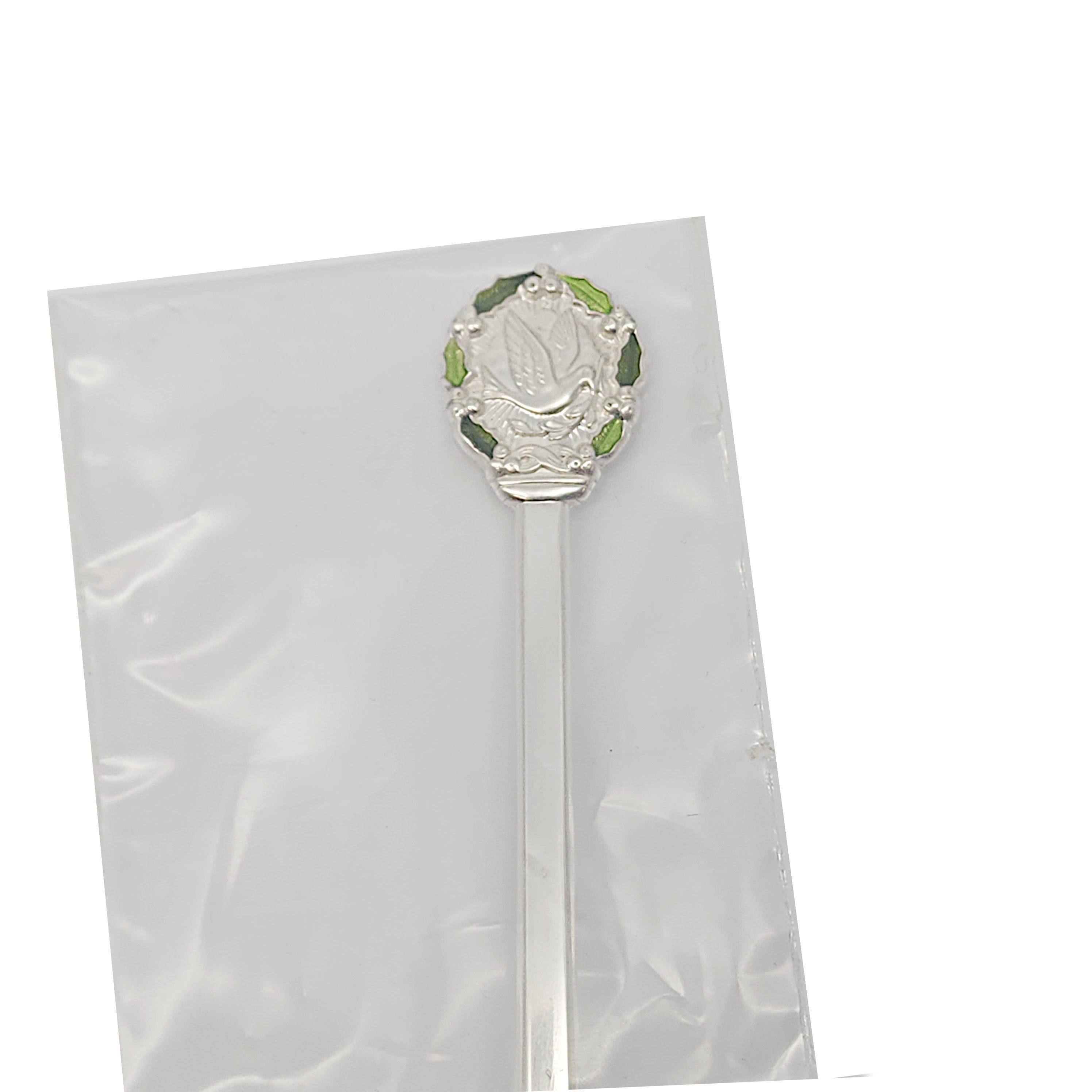 Gorham sterling silver Christmas spoon from 1977, sealed with box.

This Christmas spoon features a dove surrounded by green enamel holly leaves on one side of the handle, 