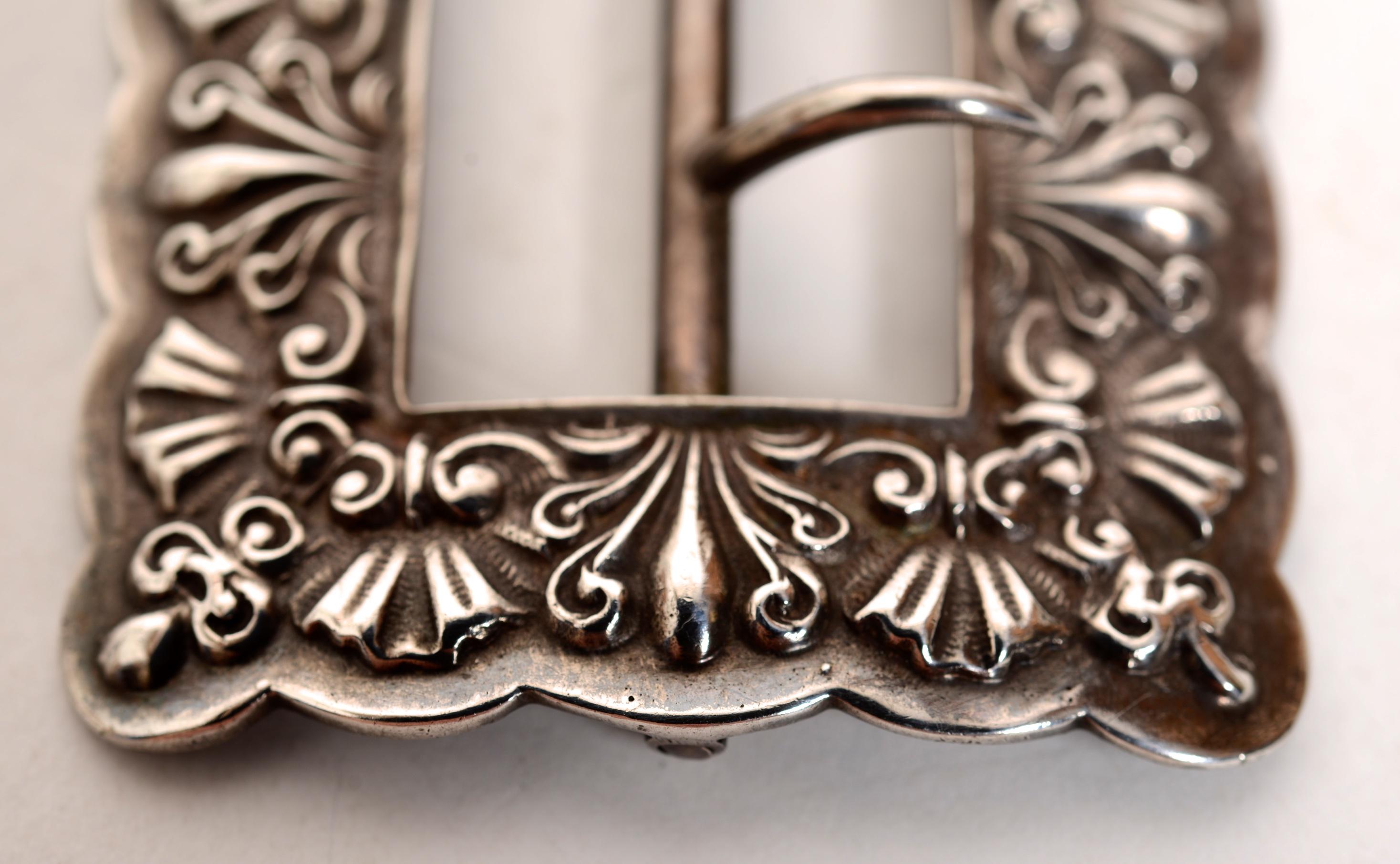 Gorham Sterling Silver Belt Buckle #144, c1888.  The design work of stylized flowers and shells is crisp and has a beautiful patina. The center section moves easily. There has been no repairs. 
These buckles are normally worn with a black Petersham