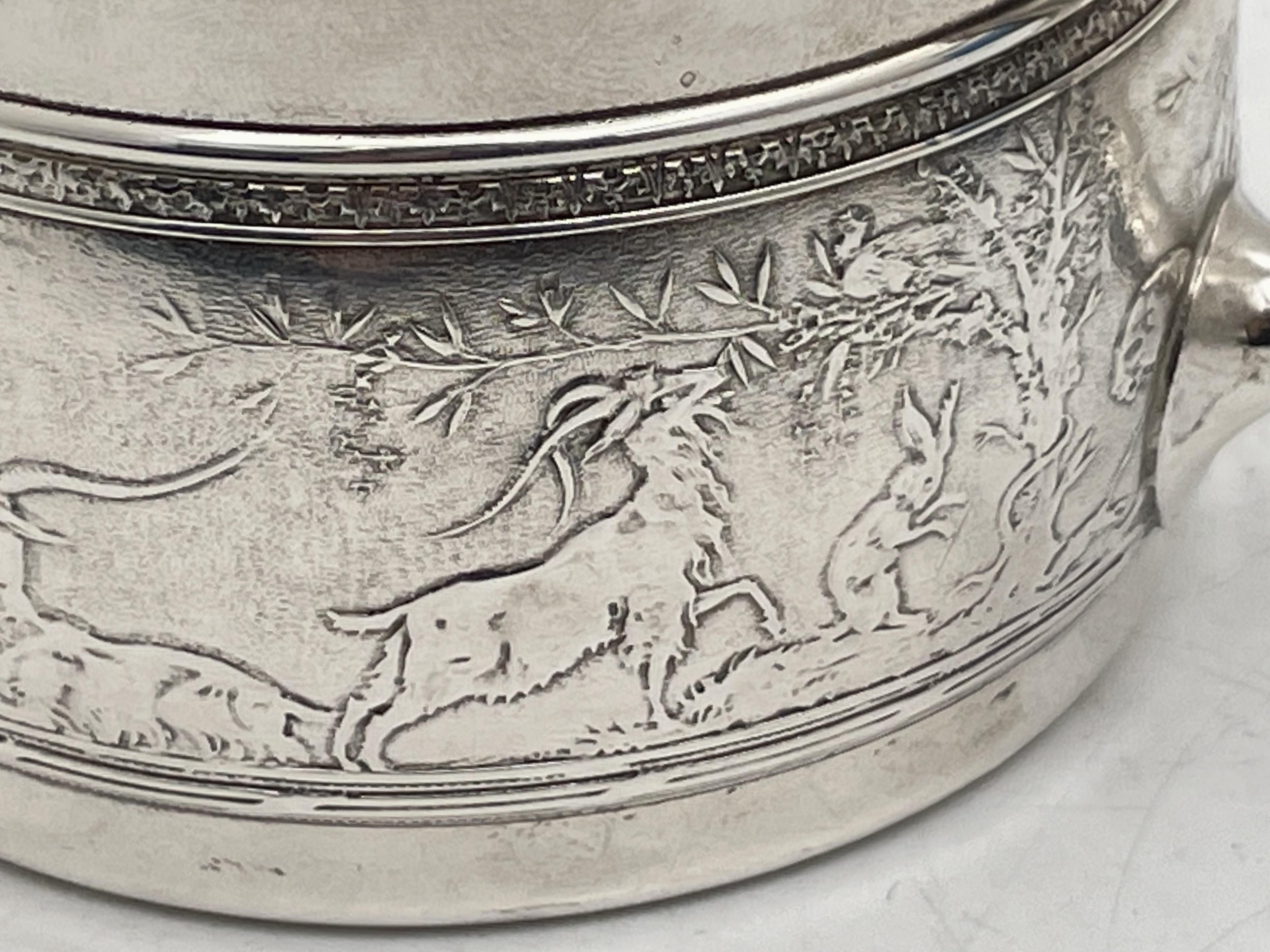 Gorham sterling silver child's or christening mug, made in the early 20th century, gilt inside, adorned with acid-etched motifs including animals, human figures, and trees. It measures 3 1/4'' in height by 3 1/4'' in diameter at the top, weighs 5.1
