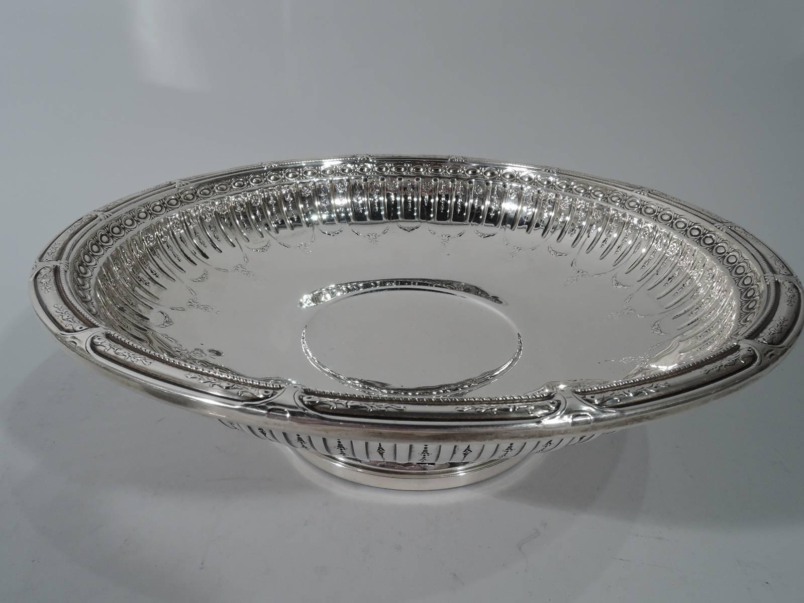 French neoclassical sterling silver bowl in Marie Antoinette pattern. Made by Gorham in Providence in 1953. Round and shallow on stepped foot. Chased ornament: Alternating flutes and flowers with garlands. Rim has tubular frames with flowers.
