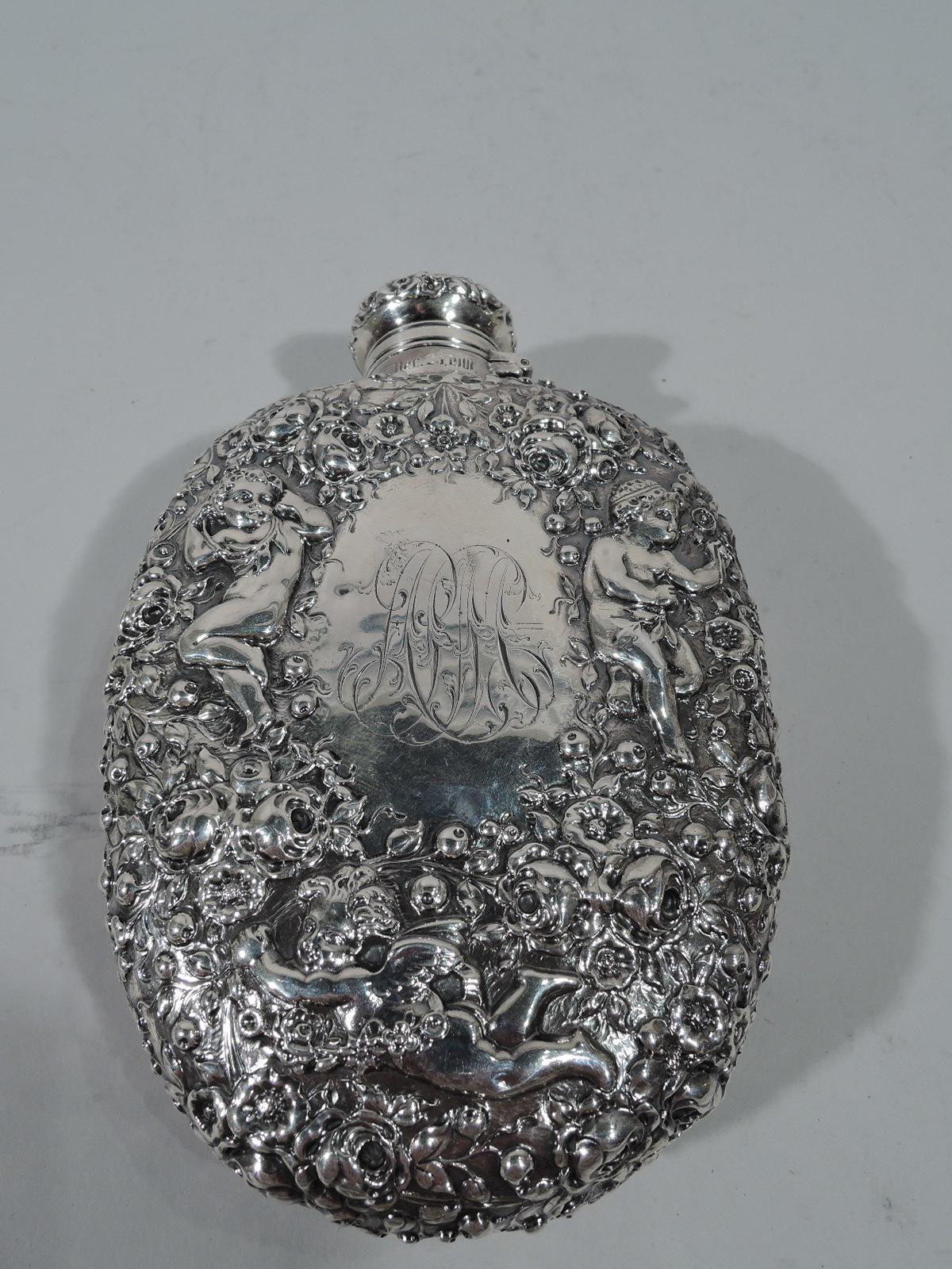 Turn-of-the-century sterling silver flask. Made by Gorham in Providence. Curved body, short neck, and hinged and cork-lined cover. Allover dense repousse cherubs frolicking amidst the roses. On back is oval frame engraved with interlaced dense