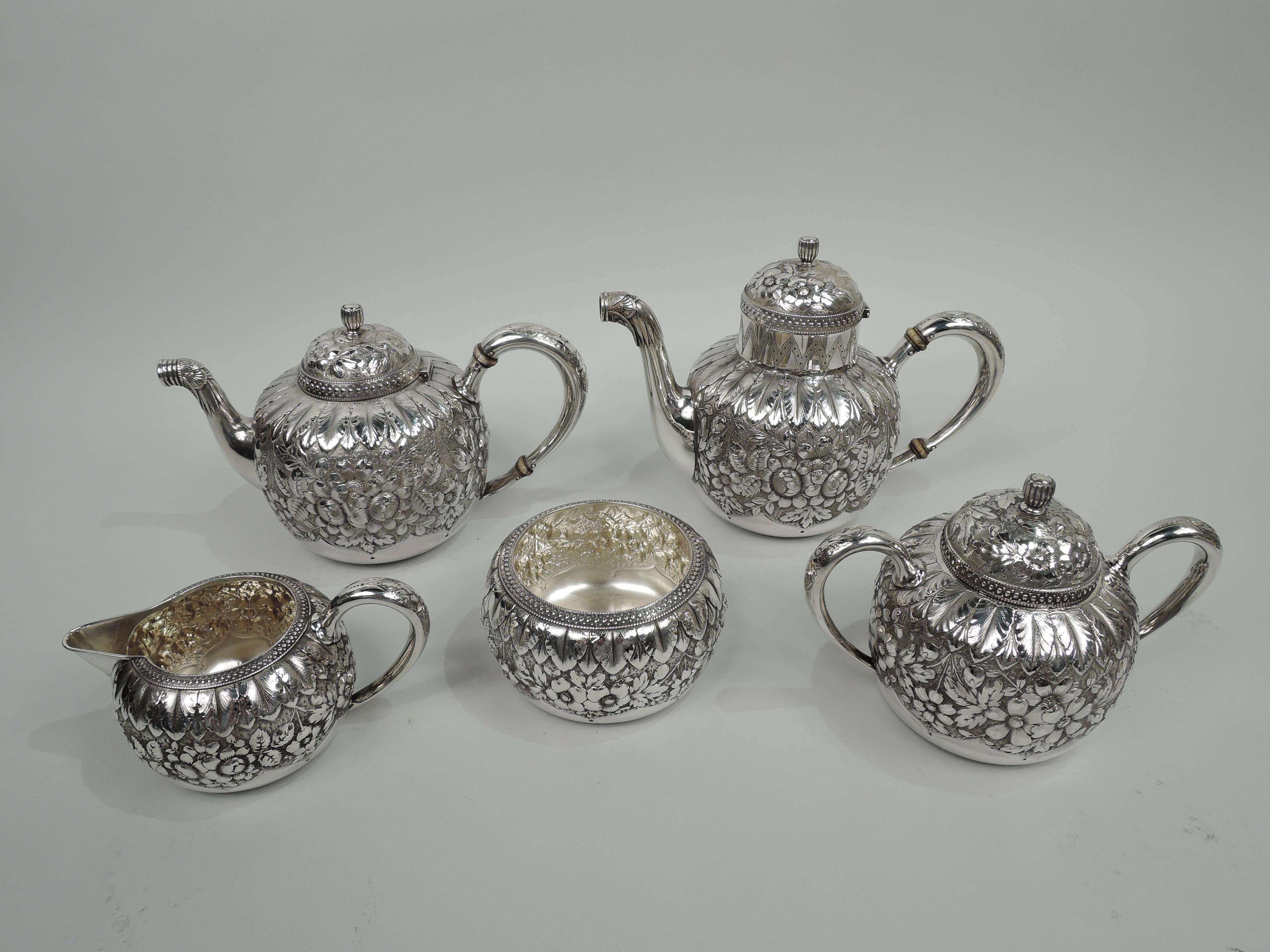 Victorian Classical sterling silver coffee and tea set. Made by Gorham in Providence in 1885. This set comprises 6 pieces: Coffeepot, teapot, creamer, sugar, and waste bowl. Each: Round body with floral repousse between chased and engraved