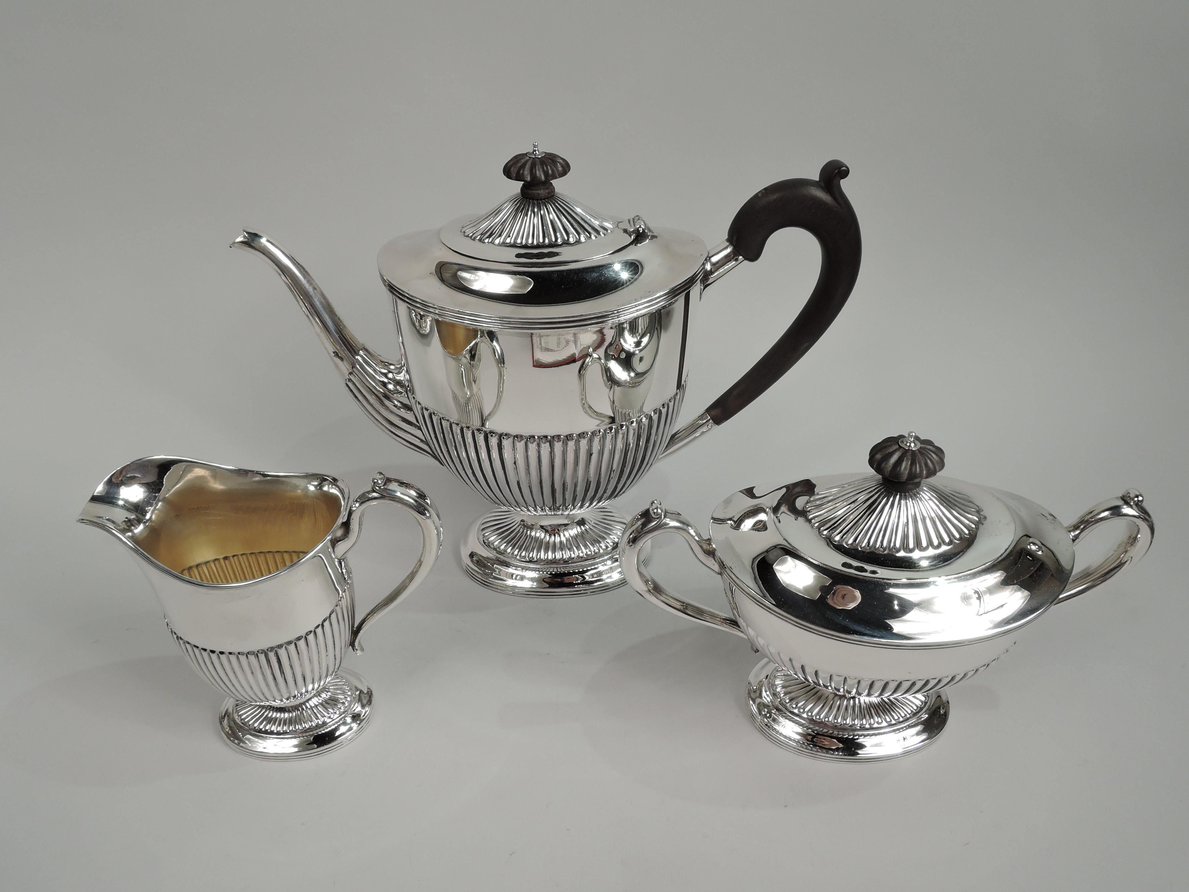 Victorian Neoclassical sterling silver coffee set. Made by Gorham in Providence in 1890. This set comprises 3 pieces: Coffeepot, creamer, and sugar. Ovoid bodies, raised oval feet, reeded rims, high-looping capped handles (coffeepot stained-wood),