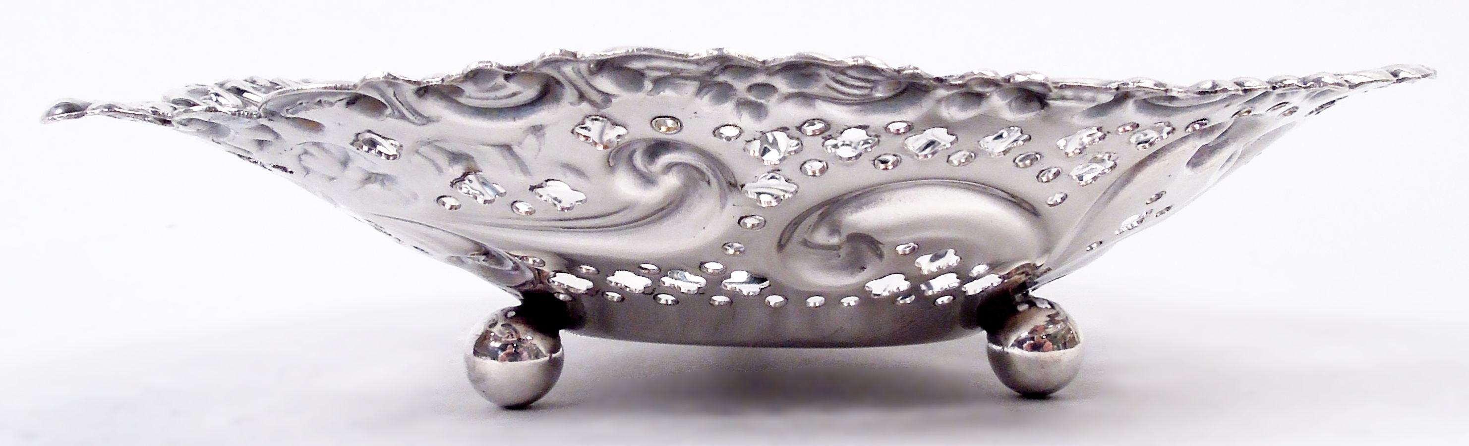Victorian Rococo sterling silver heart dish. Made by Gorham in Providence, ca 1950. Solid well and tapering sides with embossed bow-tied ribbon and scrolls, and pierced circles and quatrefoils. Irregular rim with scrolls and flowers. Three ball
