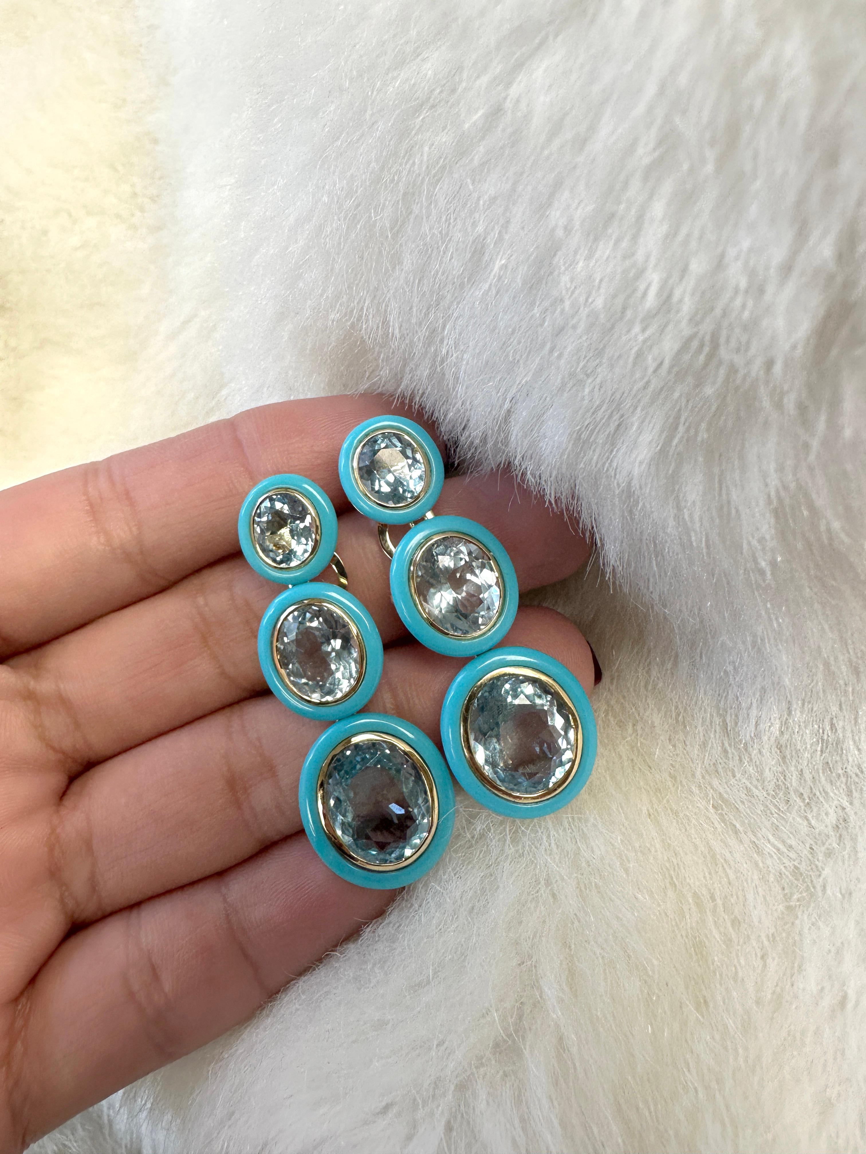 These 3 tier Oval Shape Blue Topaz & Turquoise Earrings in 18K Yellow Gold are a stunning piece of jewelry from the 'Melange' Collection. The earrings feature three oval-shaped Blue Topaz gemstones, with turquoise border. The gemstones are set in