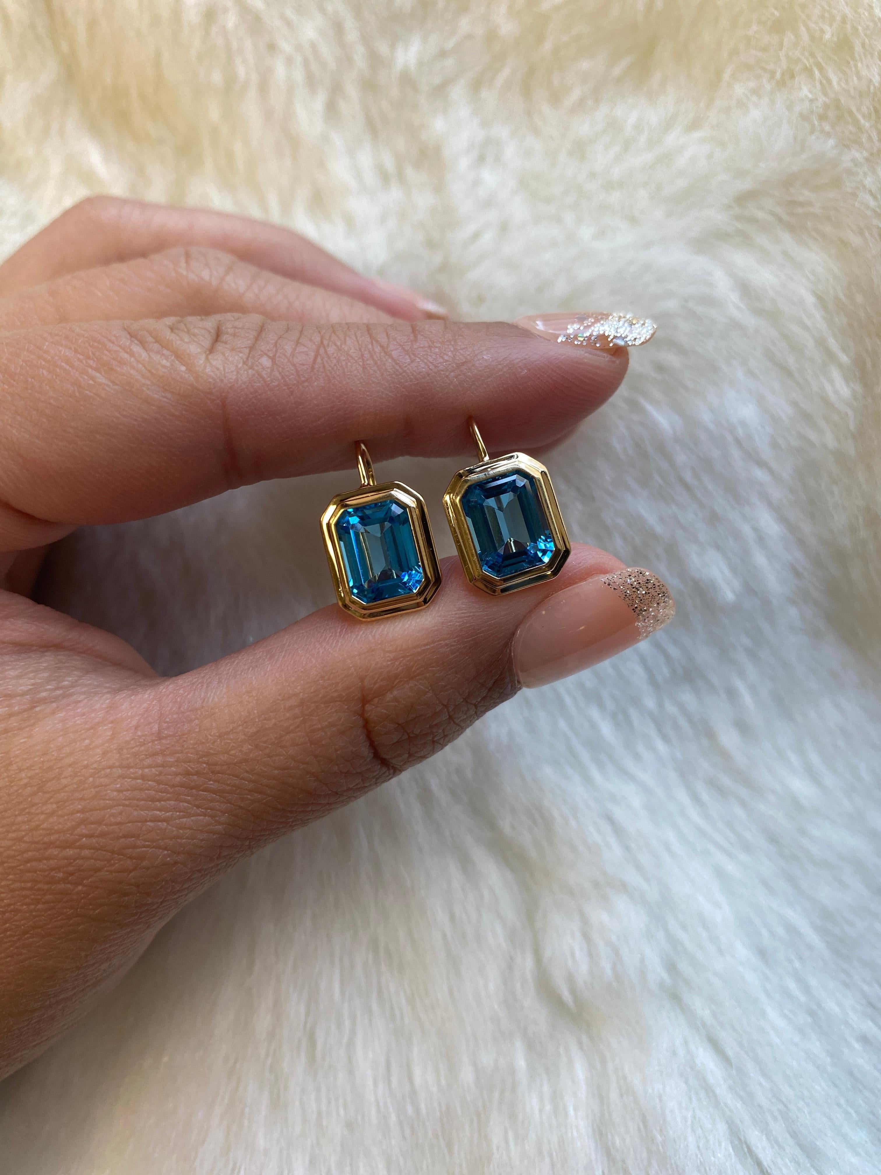 These Blue Topaz Emerald Cut Bezel Set Earrings on Wire in 18K Yellow Gold from the 'Manhattan Collection are a stunning and sophisticated jewelry piece. These earrings feature exquisite blue Topaz gemstones with an elegant emerald cut, cradled in a